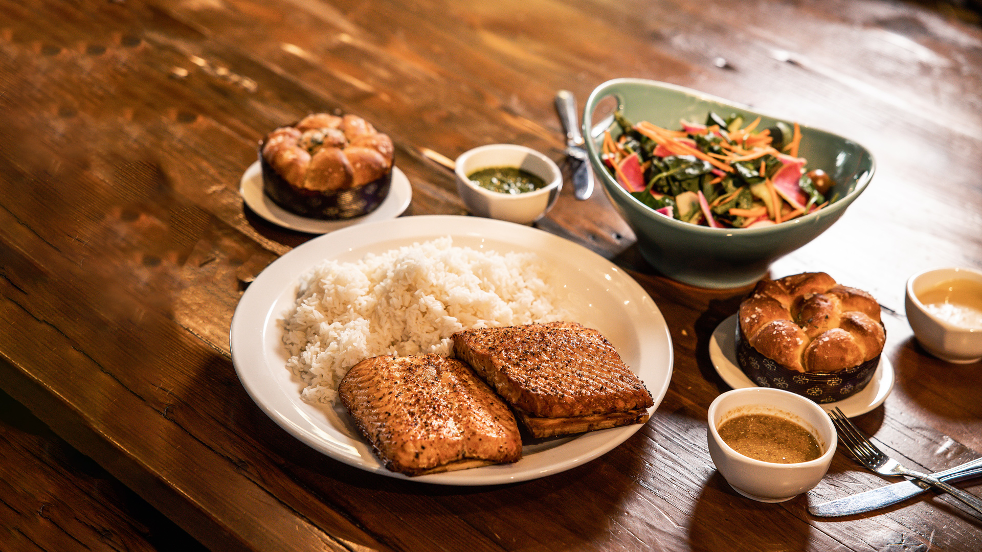 Cedar Plank Salmon Meal - Roasted cedar plank salmon (14 oz) served with steamed jasmine rice, fresh greens salad with white balsamic vinaigrette, and fluffy, pull apart Parker House rolls - choice of sauce (serves 2-3).