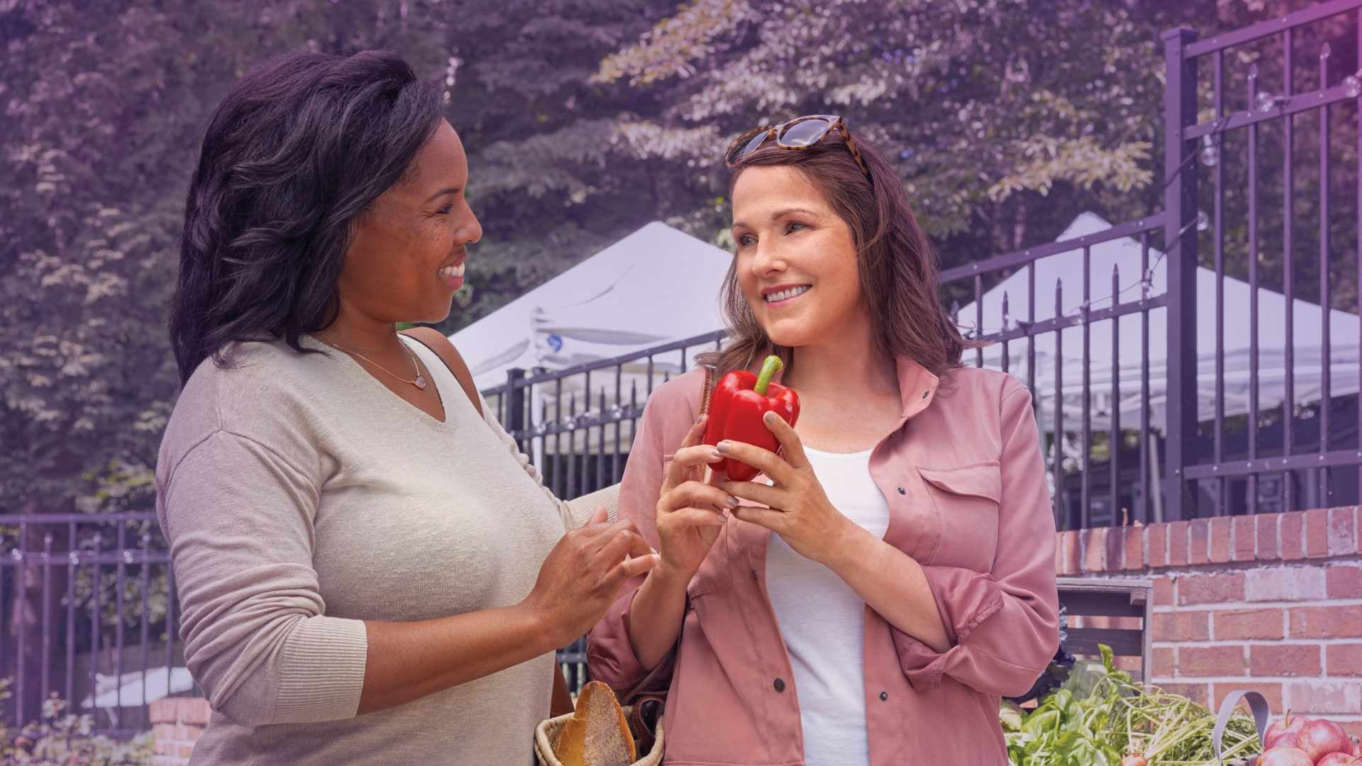 Photo of two women with one holding a chili pepper