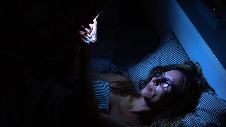 woman looking at her phone in the bed