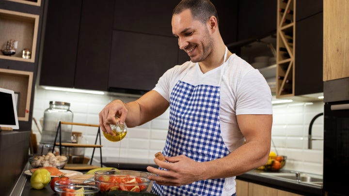 Man pouring extra virgin olive oil on salad