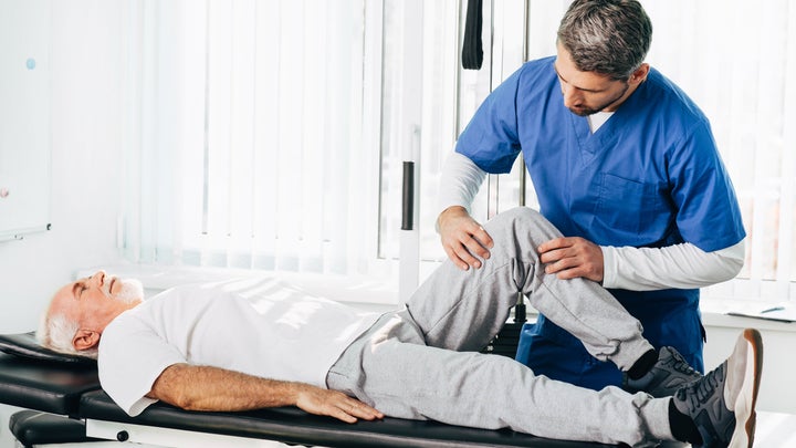 physical therapist checking the motion range of his patient's knee