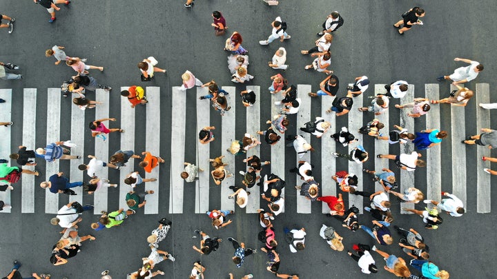 an eclectic group of people crossing a wide street, birds-eye view