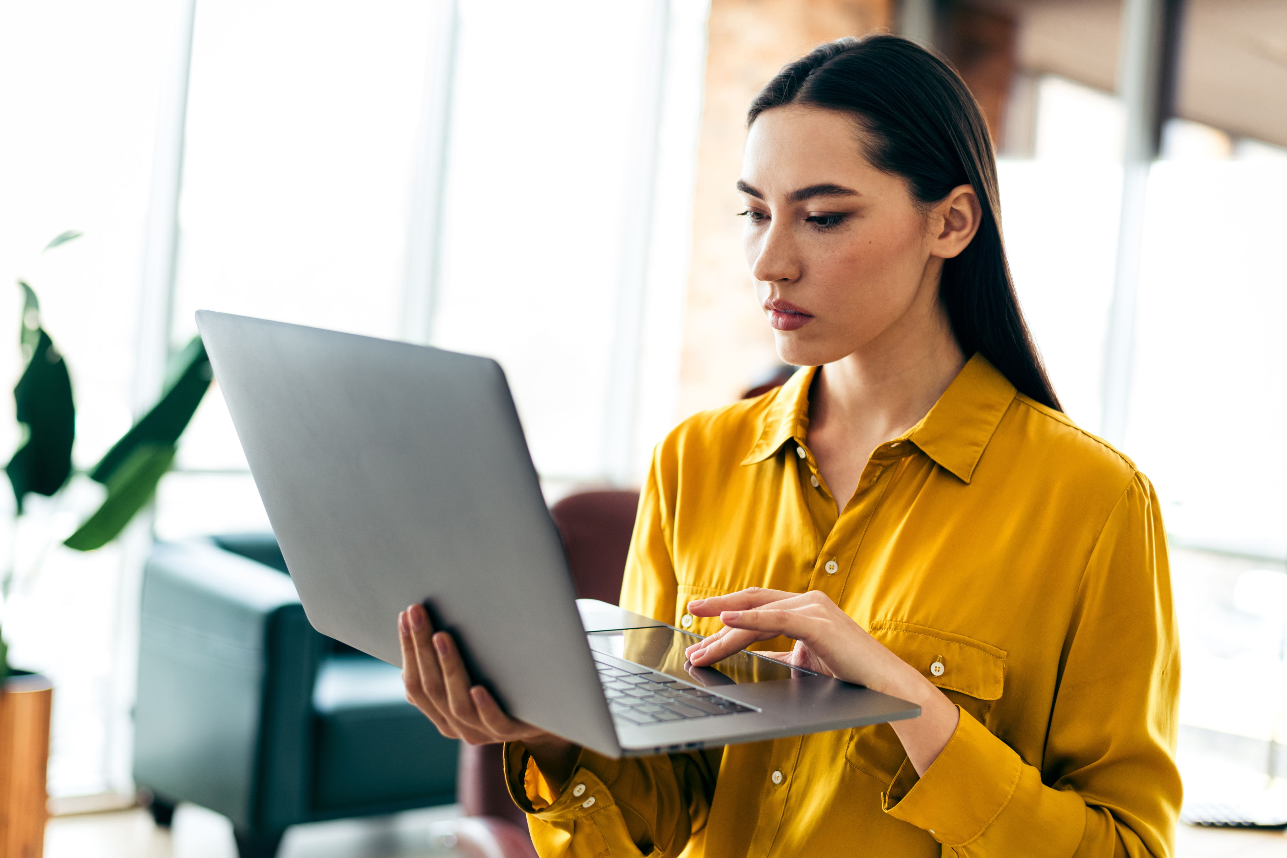 Woman holding a laptop and looking at its screen