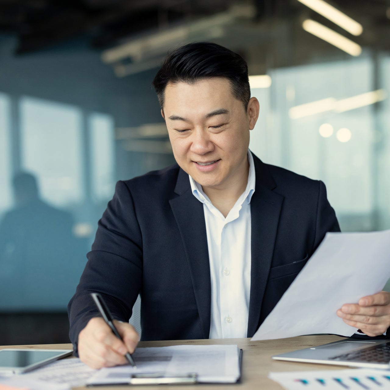 A professional man working on a desk with some papers holding a pen.