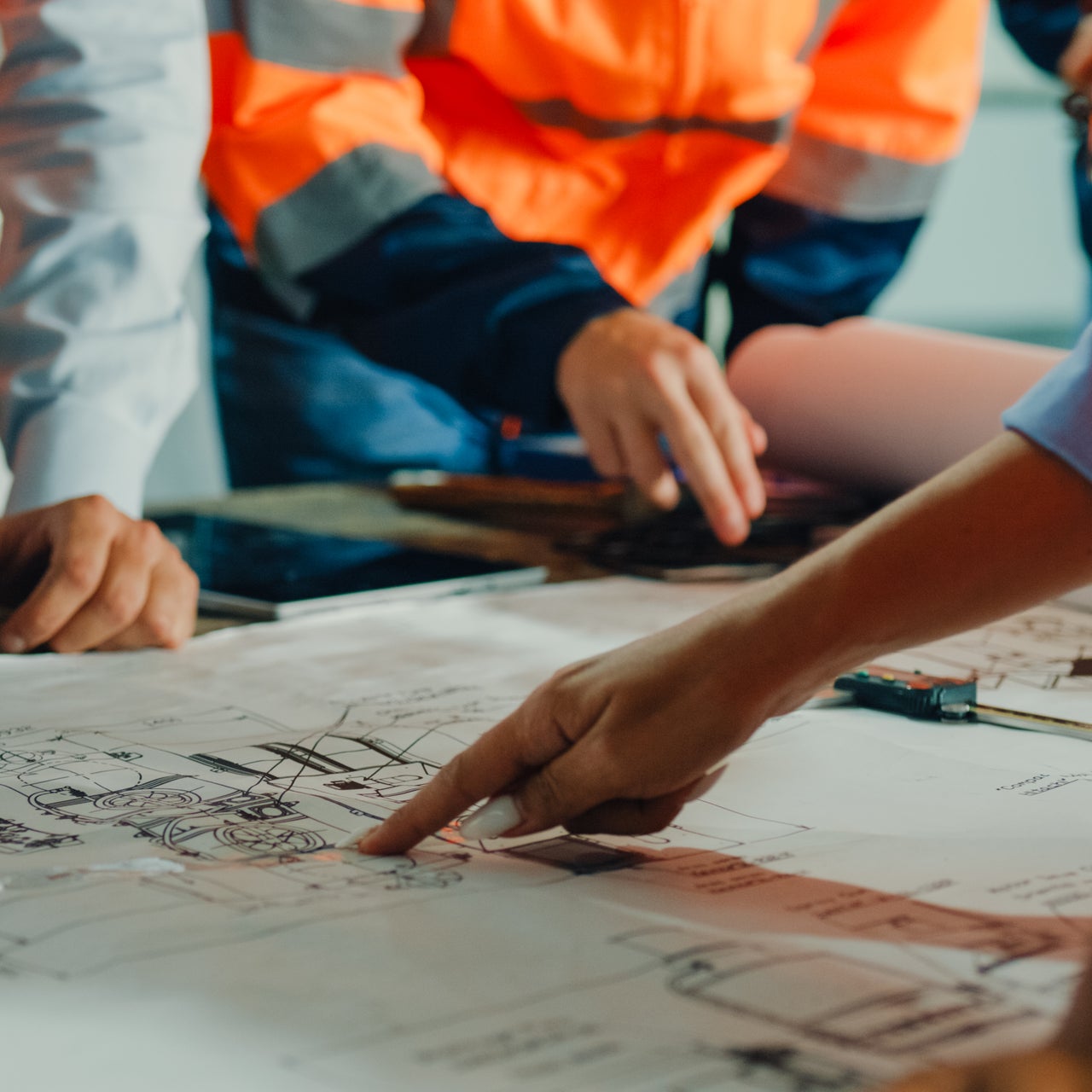 City planners and engineers in safety vests evaluating municipal infrastructure blueprints for community development.