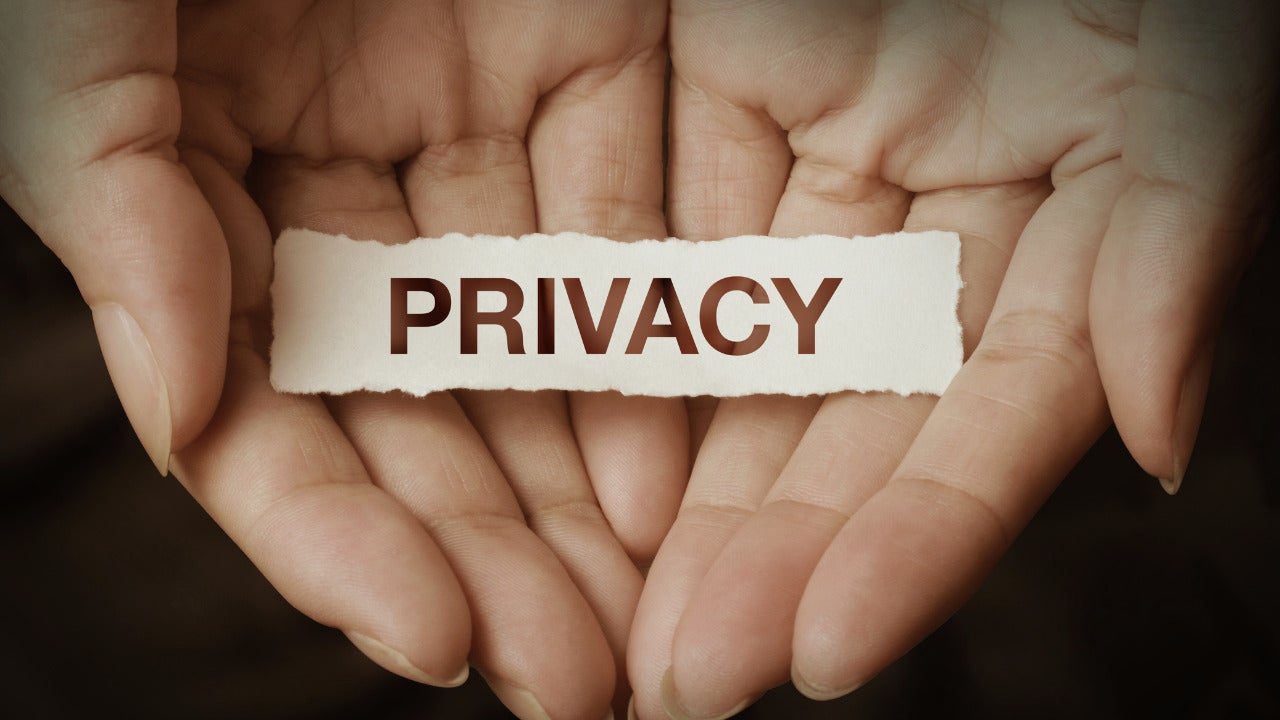 An image of two hands holding a piece of paper with the word privacy on it