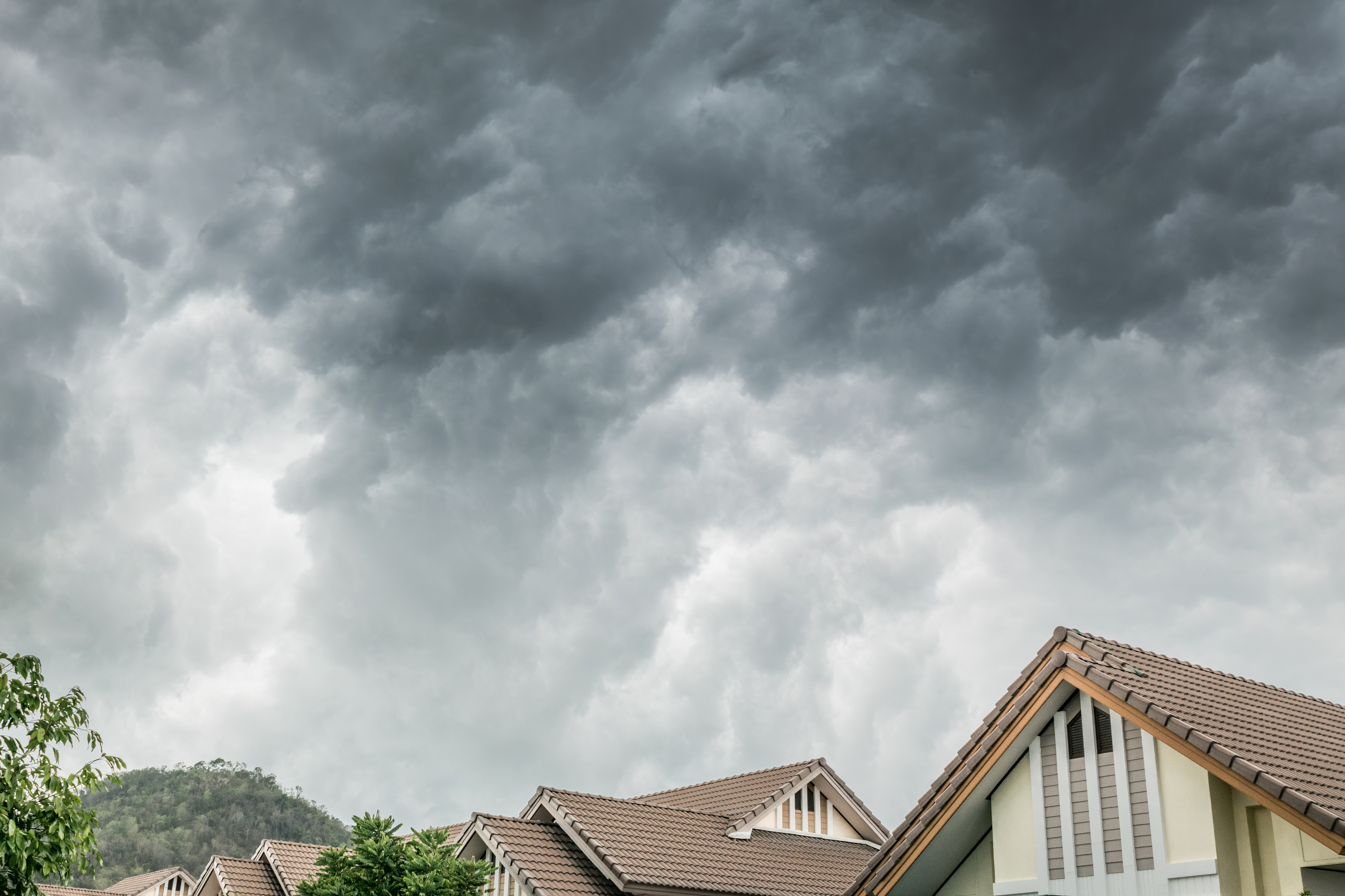 A high view of a home zoomed in on the roof with a storm coming.