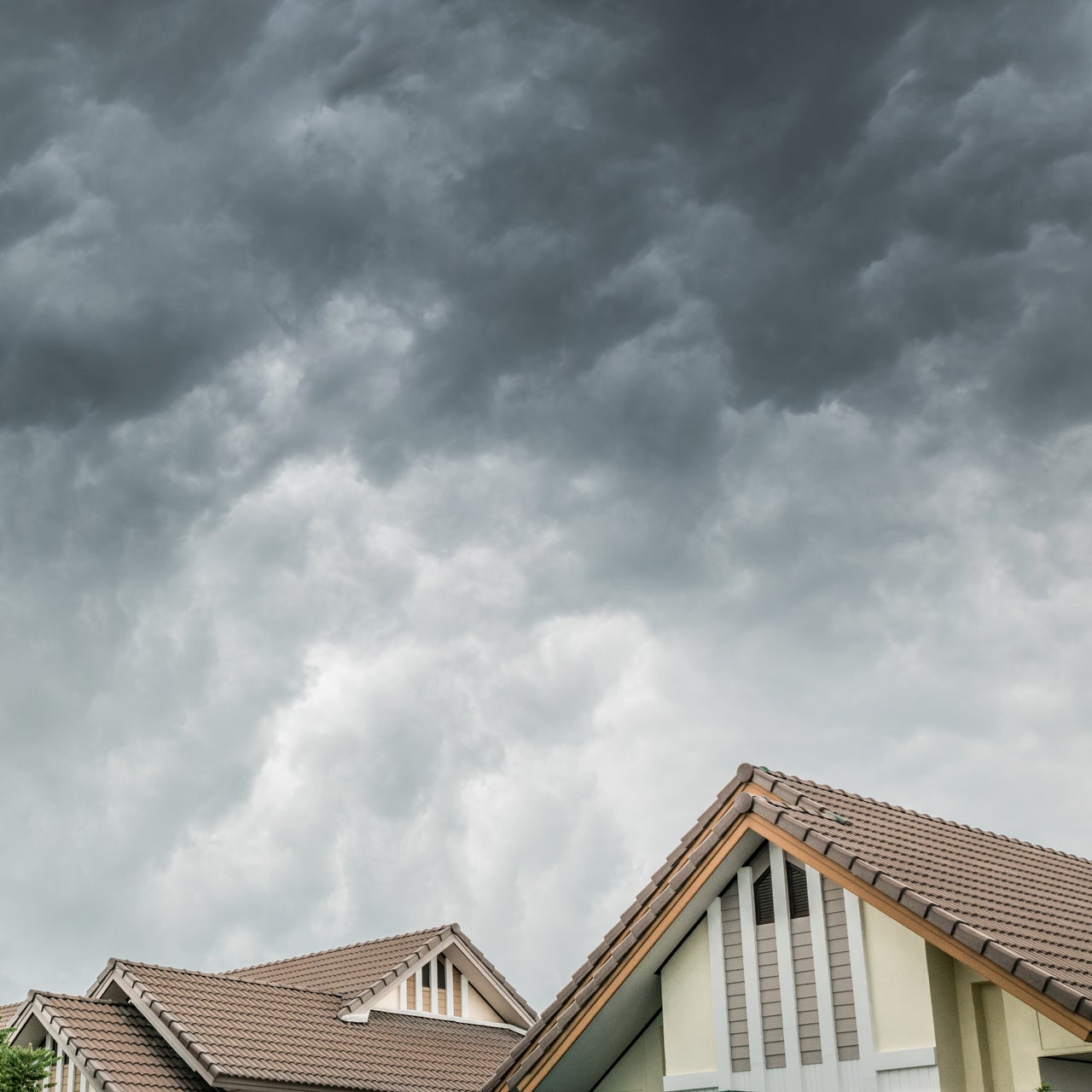 A high view of a home zoomed in on the roof with a storm coming.