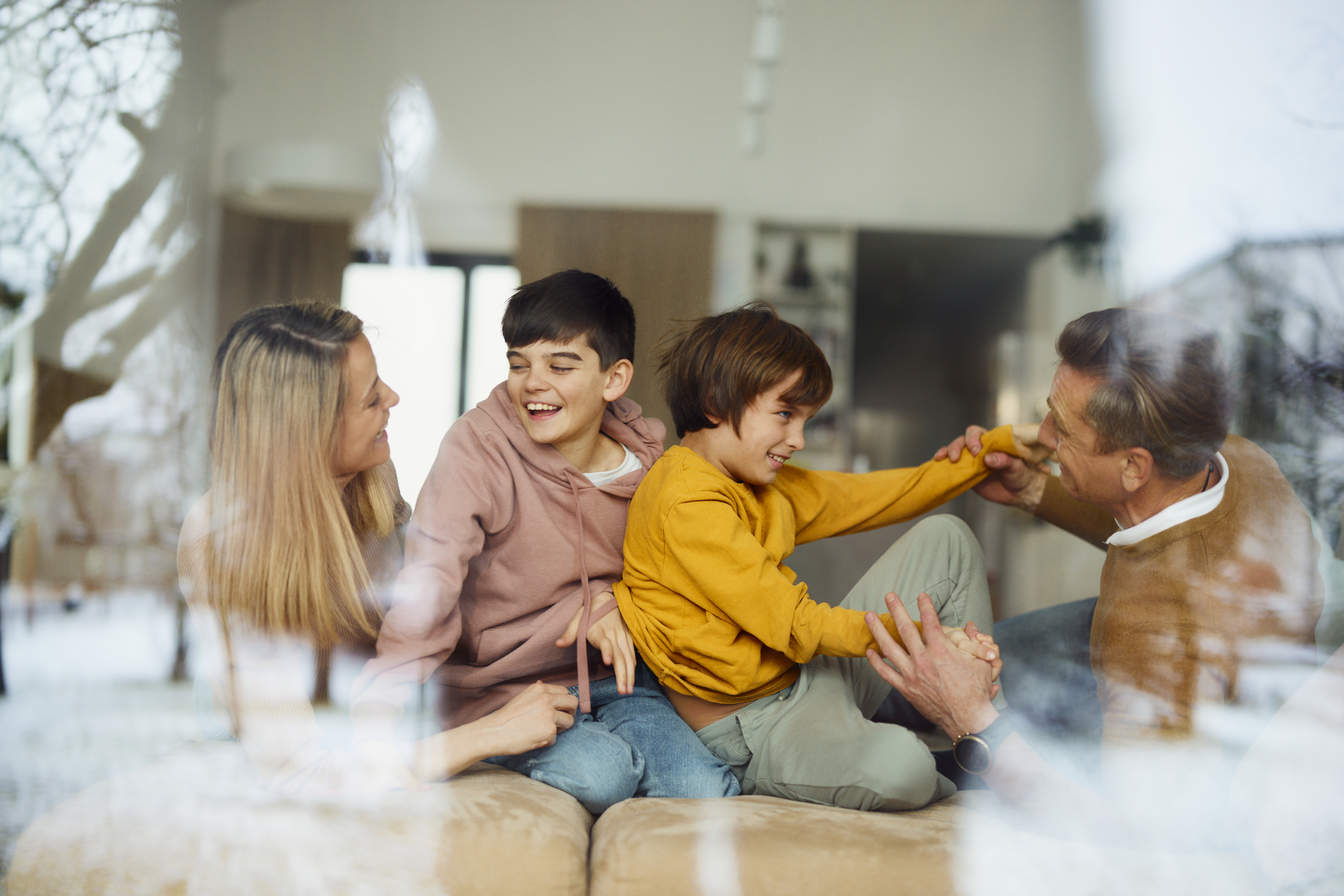 A family laughing while sitting on the couch in their new home.