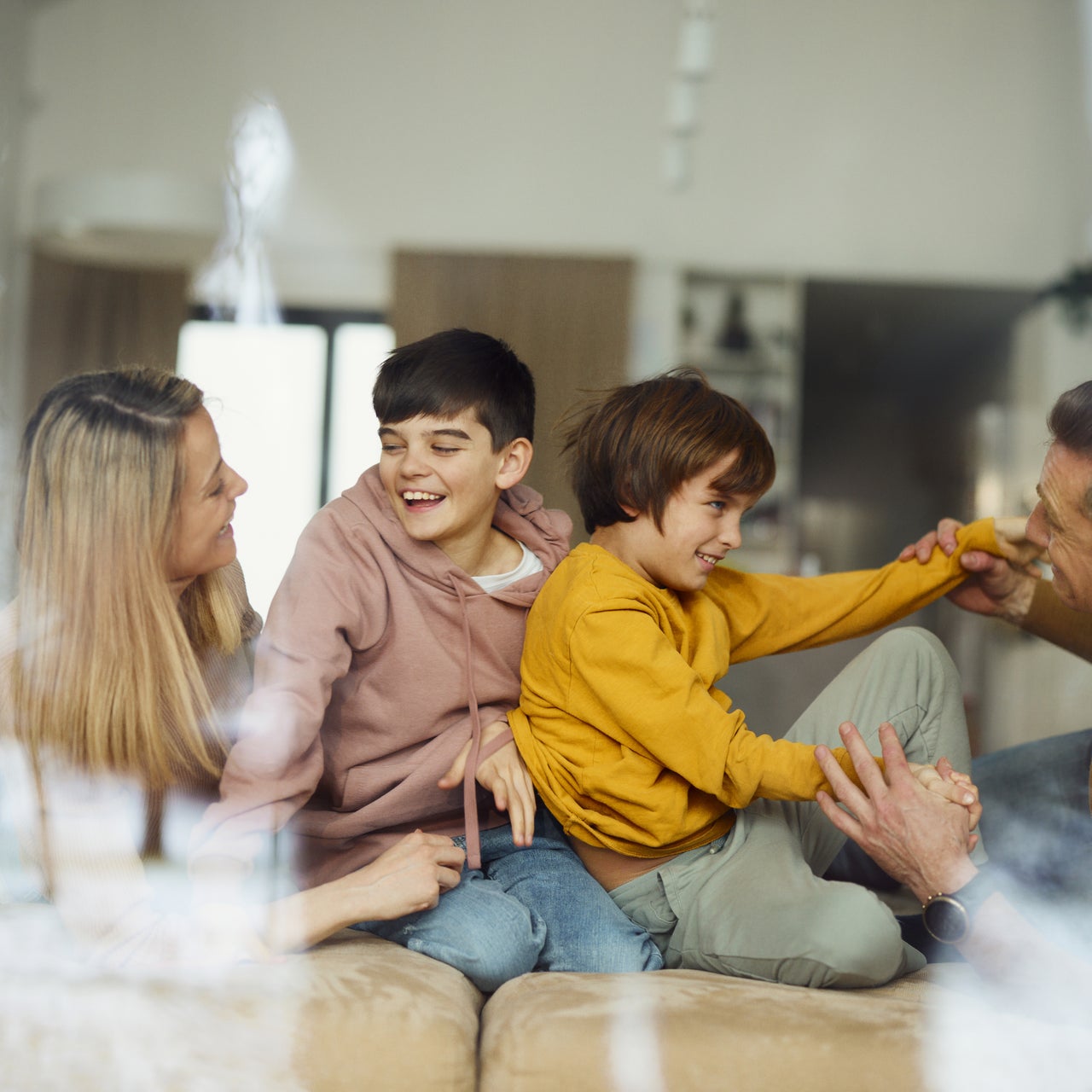A family laughing while sitting on the couch in their new home.