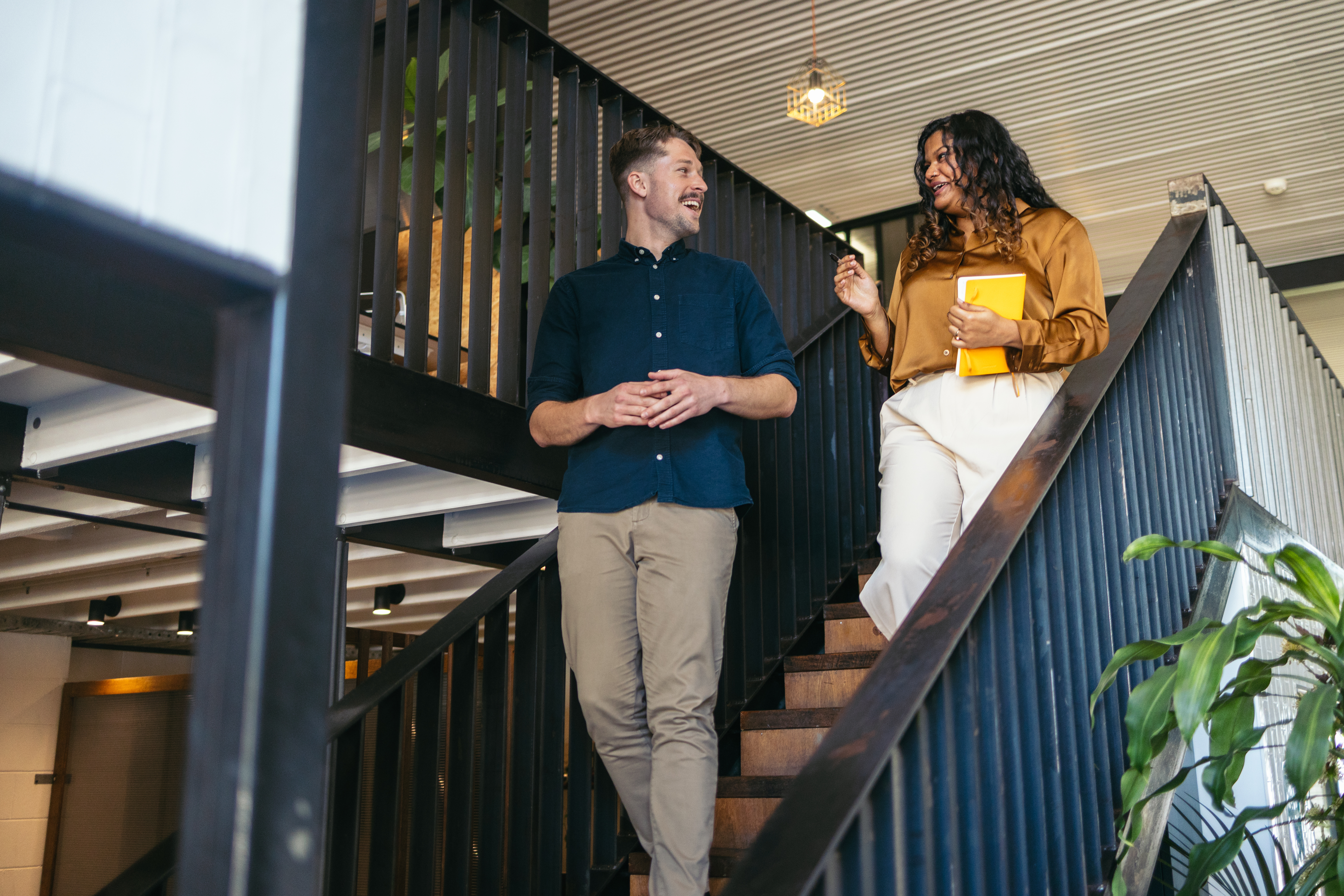 Two people are engaged in a conversation while walking down a staircase. 