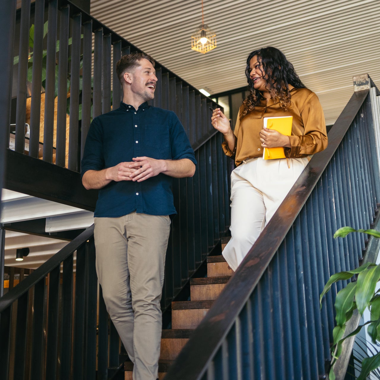 Two people are engaged in a conversation while walking down a staircase.