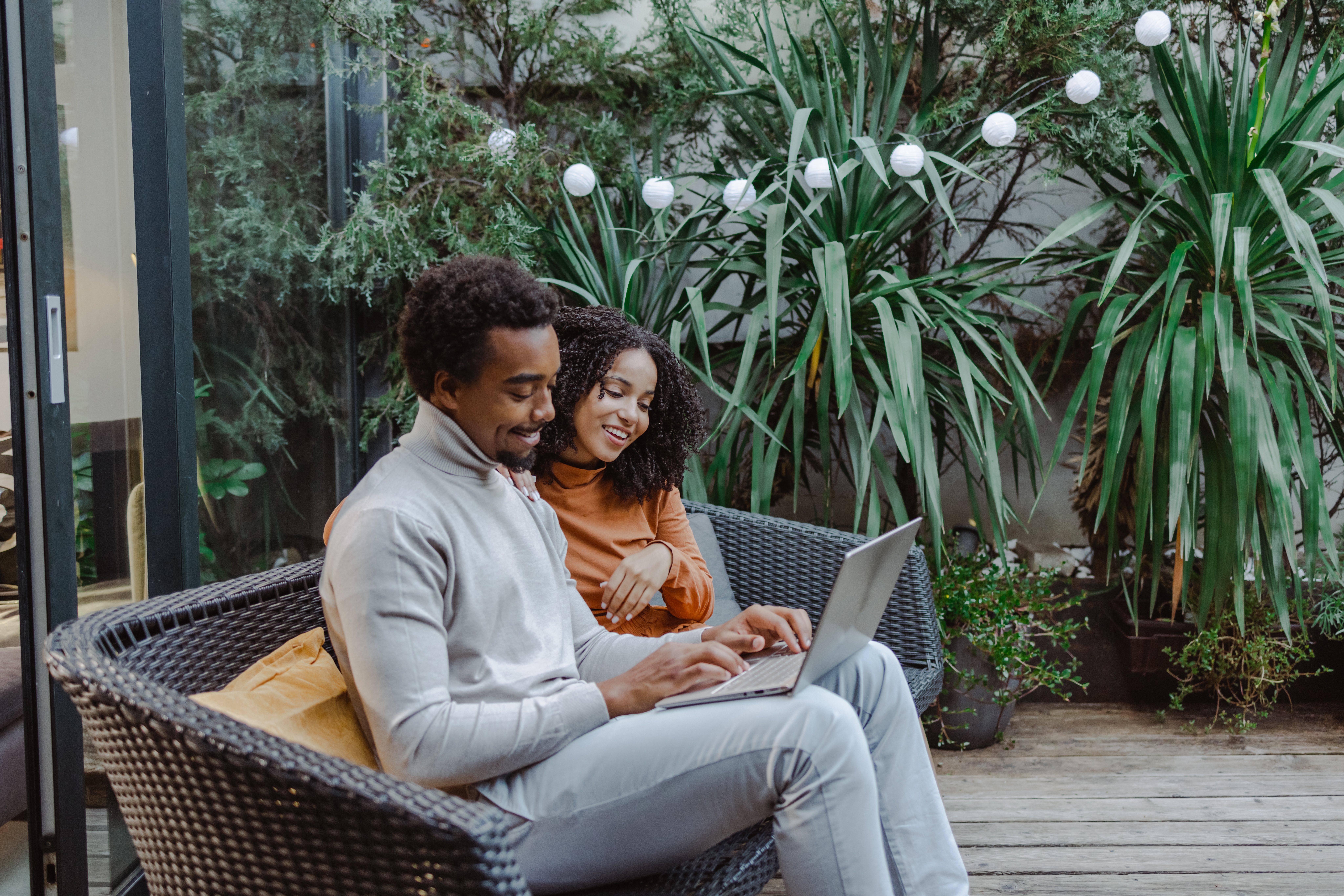 A smiling couple on their back porch, using a laptop to compare prices and shop online for home services.