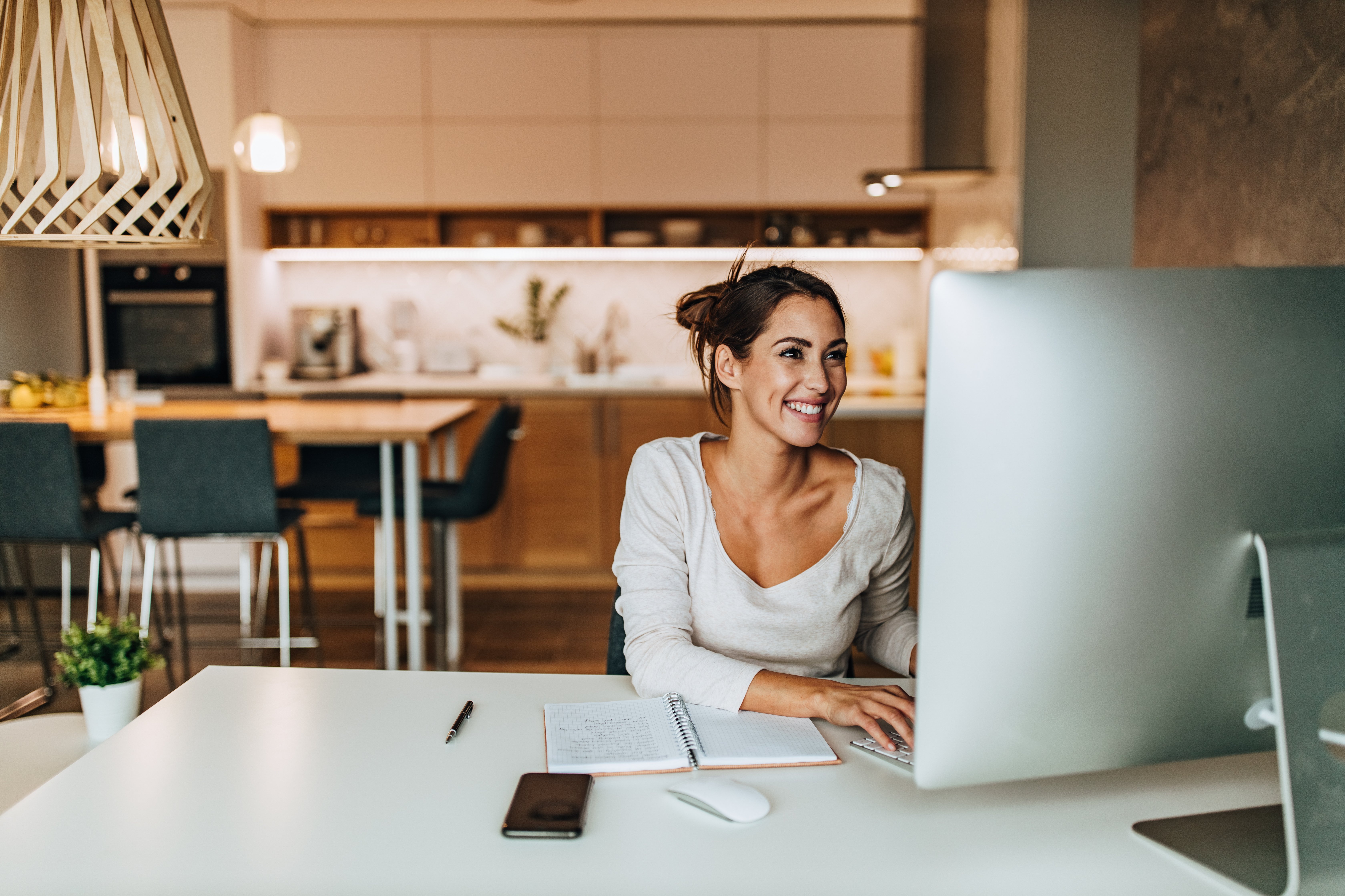 A seemingly happy young woman is working on her computer kept on her desk.