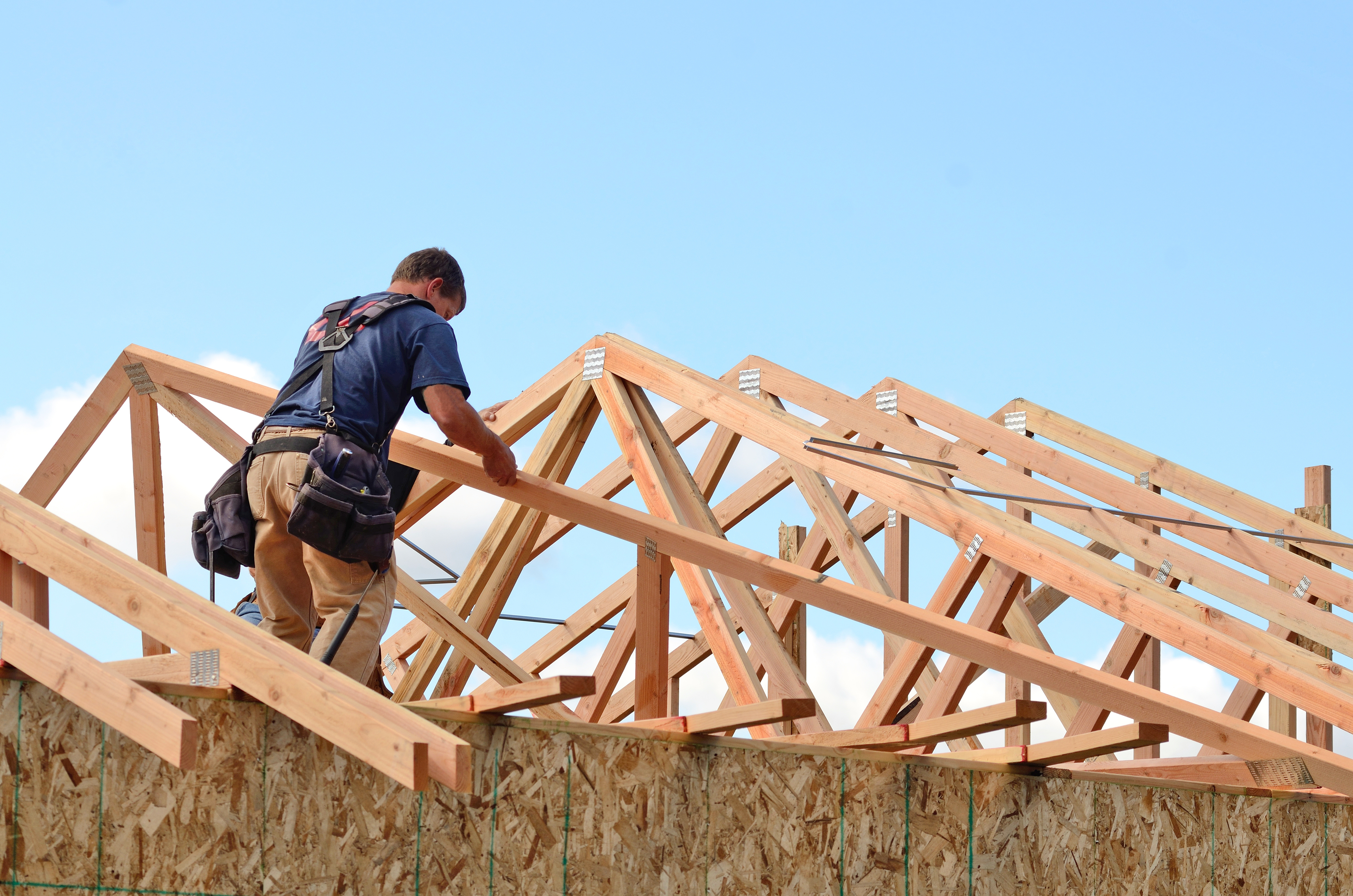 A construction worker is seen working on an under-constructed roof.