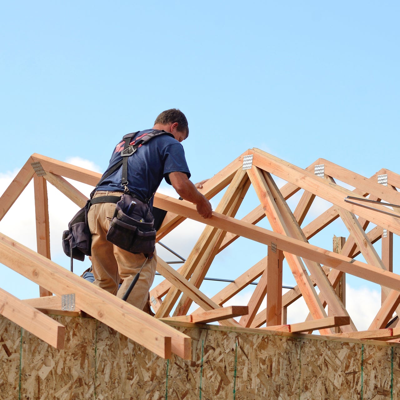 A construction worker is seen working on an under-constructed roof.