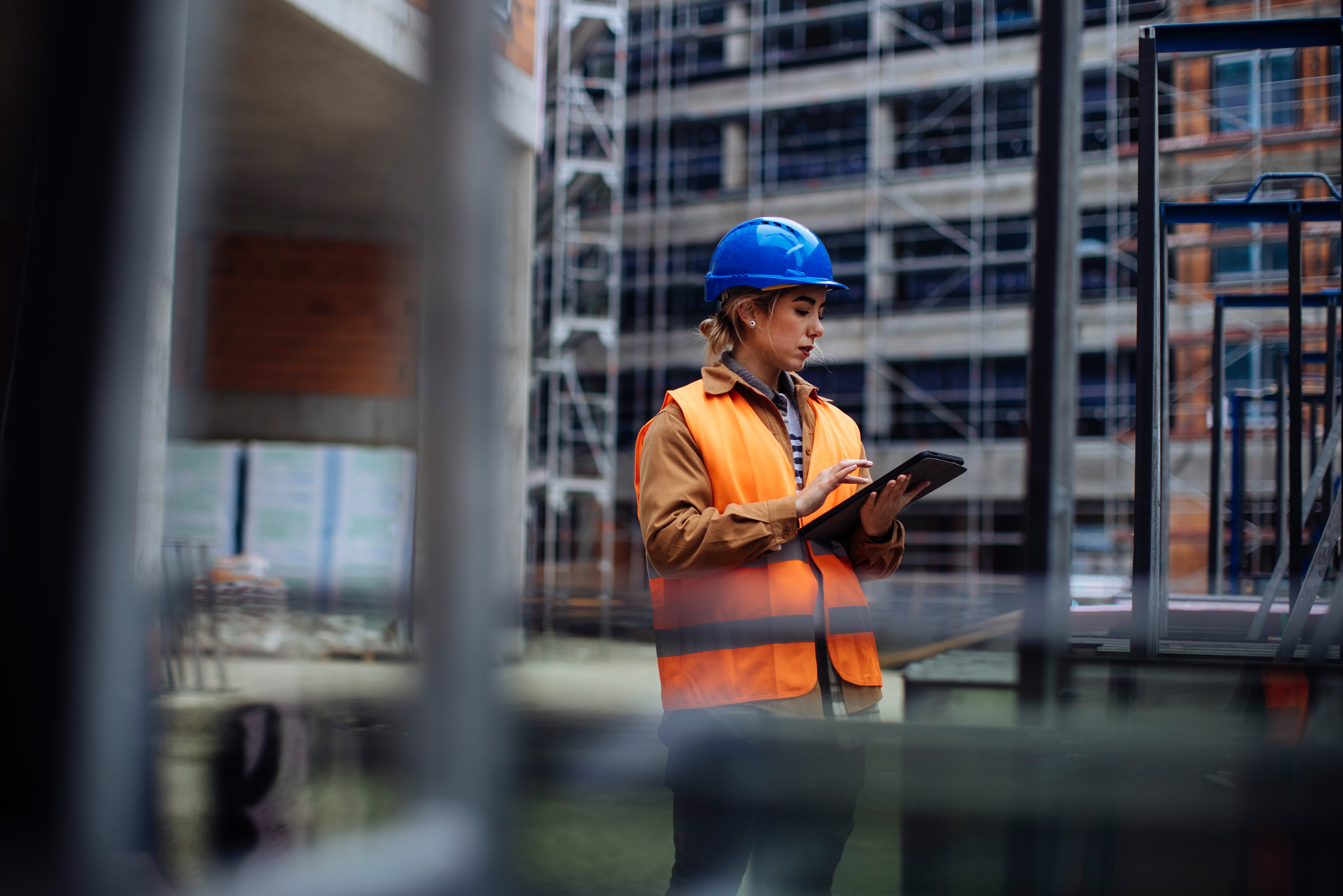 A construction worker in safety gear looking at an interactive interface on a tablet.