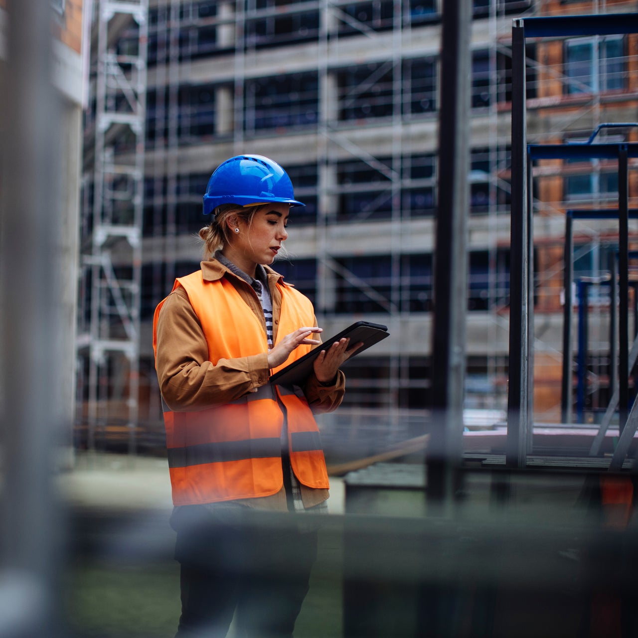 A construction worker in safety gear looking at an interactive interface on a tablet.