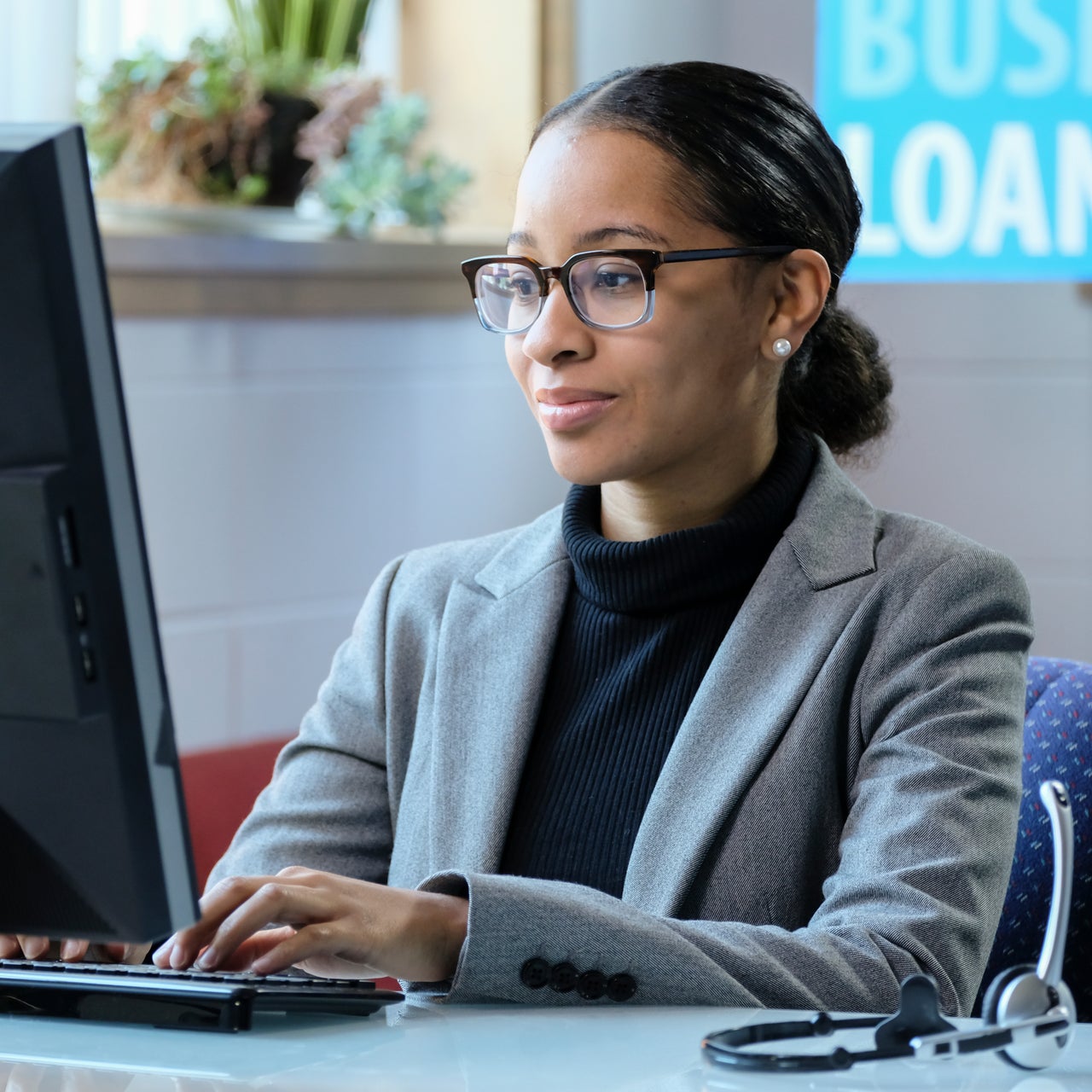 A professional woman is seen working on a laptop in a office space.