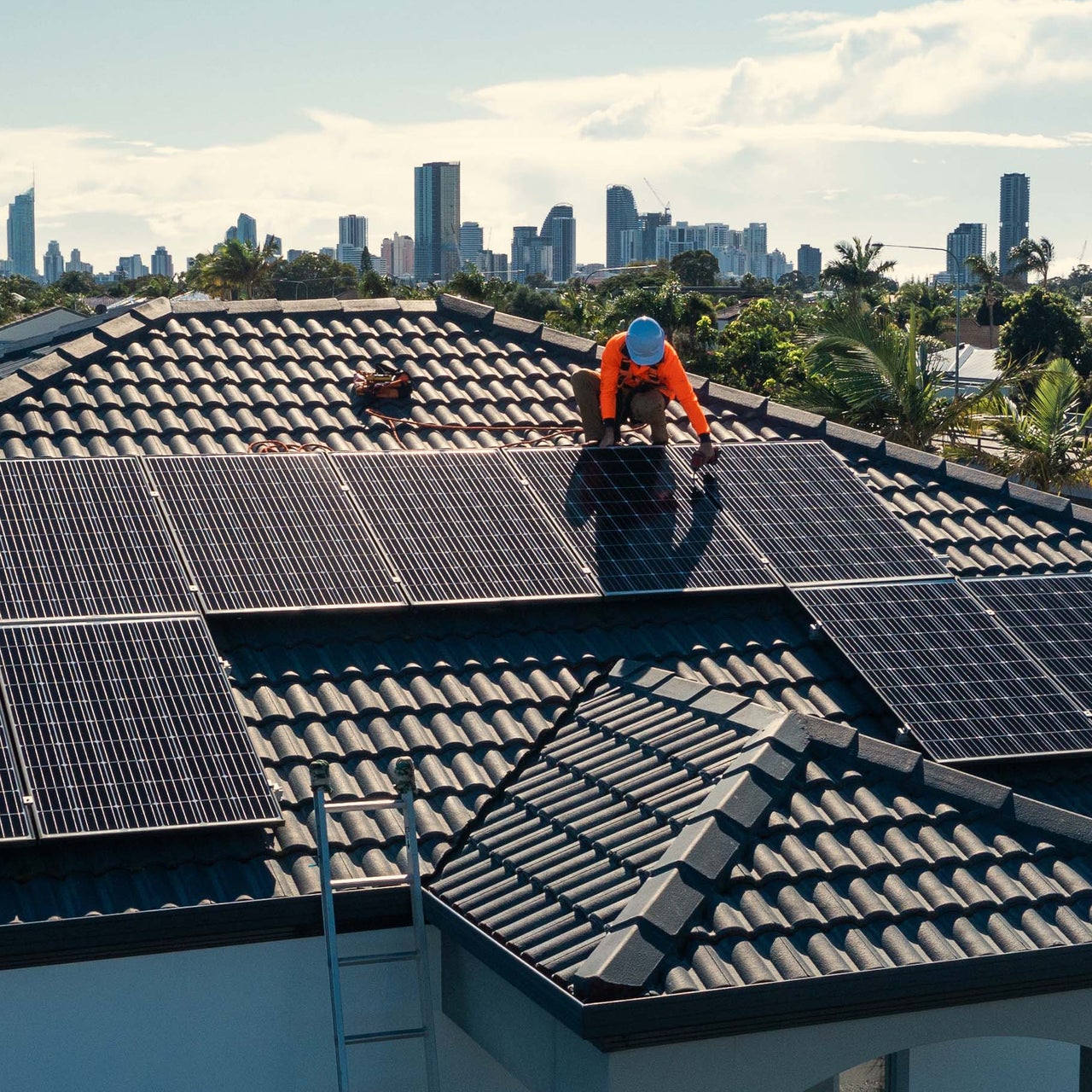 Solar panels are visible on the top of a residential property. There are also three wind mills around the house.