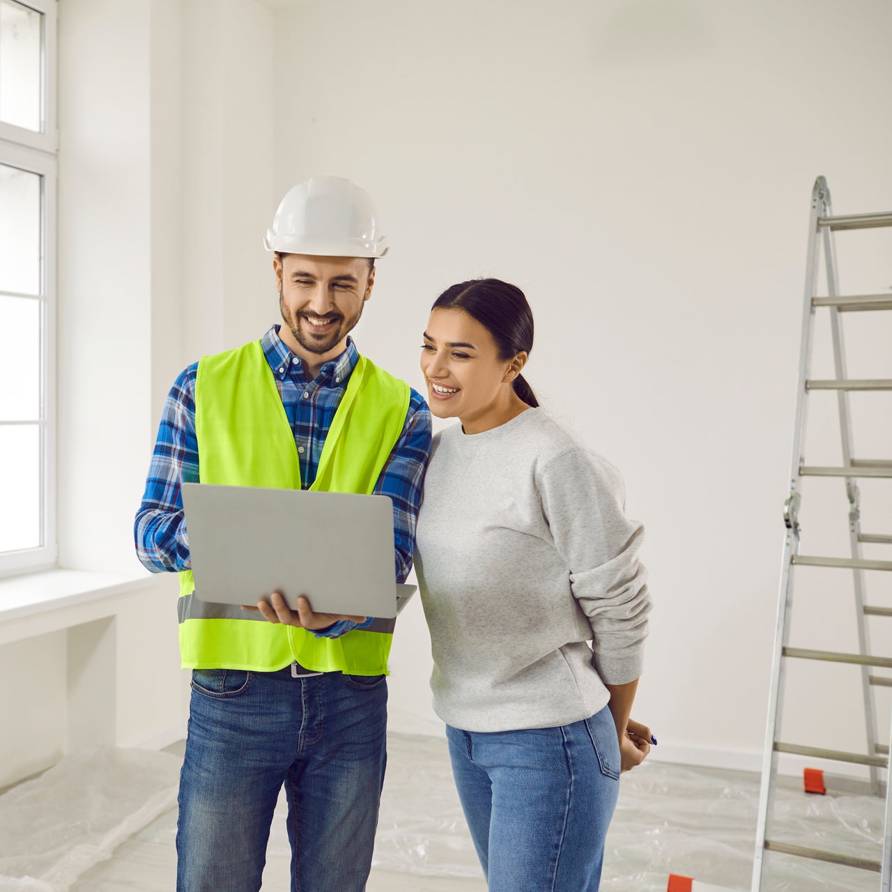 A home inspector in discussion with a young woman, who appears to be like the buyer of a property under construction