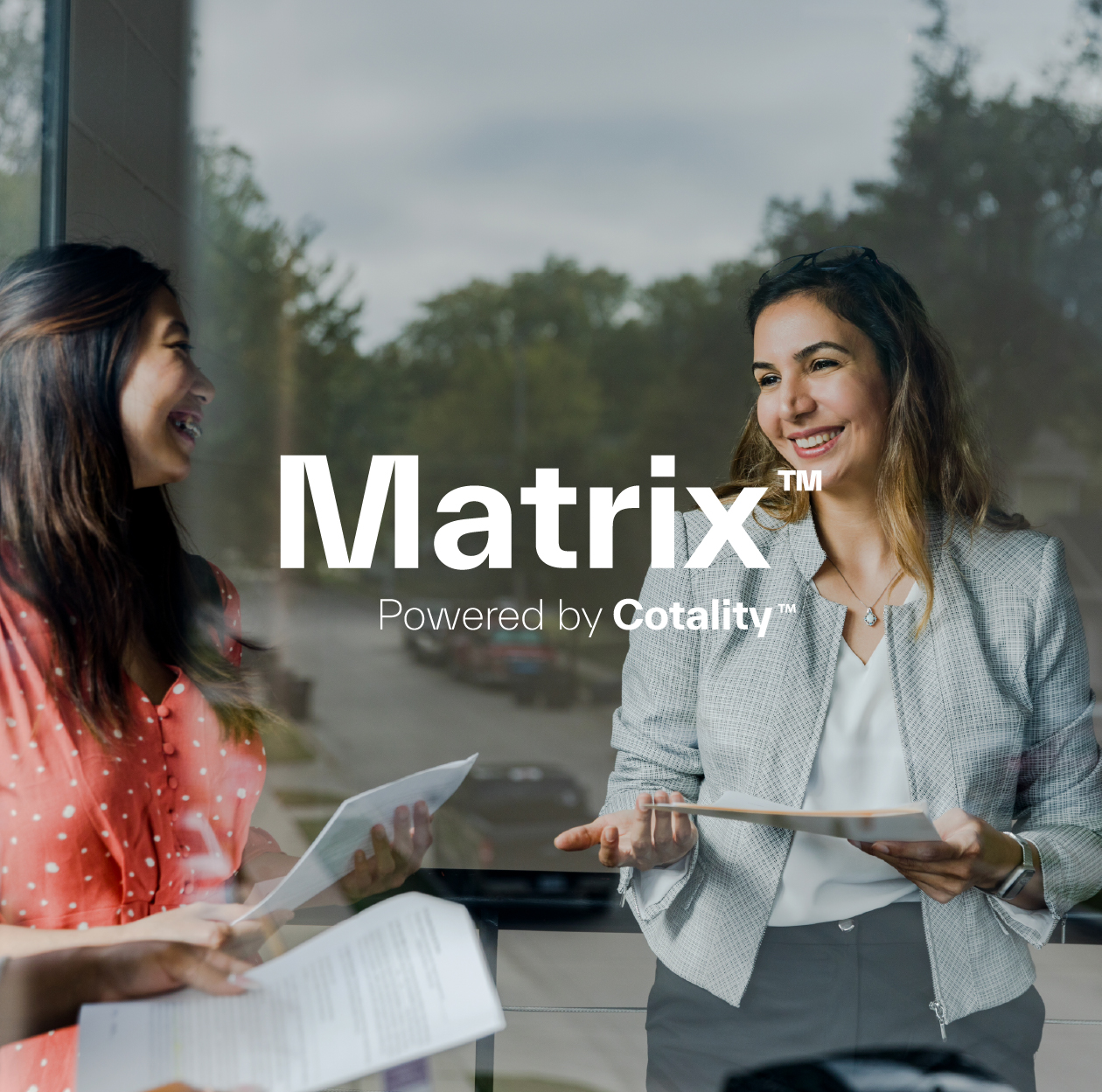 Two women in a professional setting, likely in an office or a business meeting.