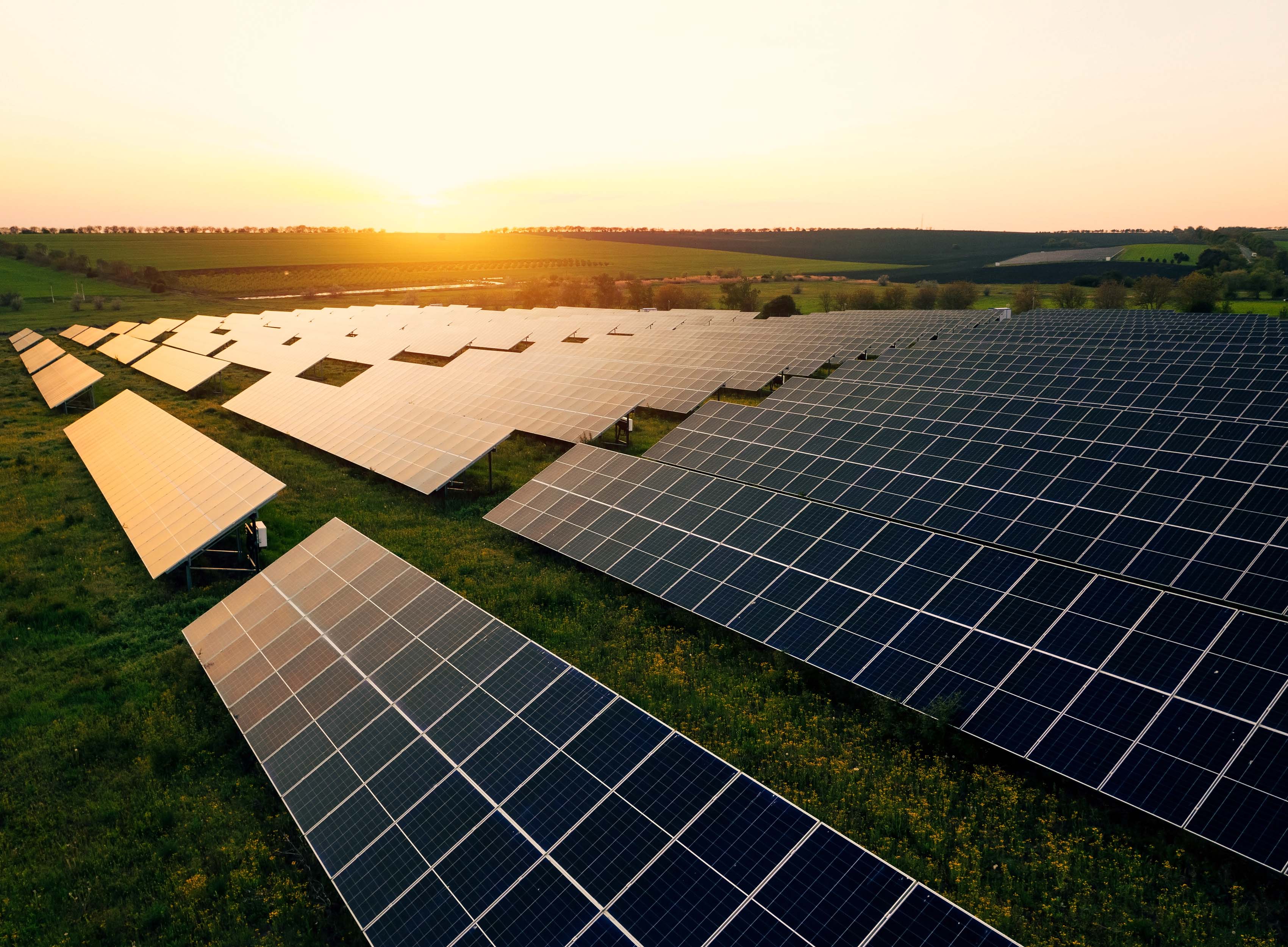 A view of numerous solar panels on the top of a property. An engineer is seen walking through it.
