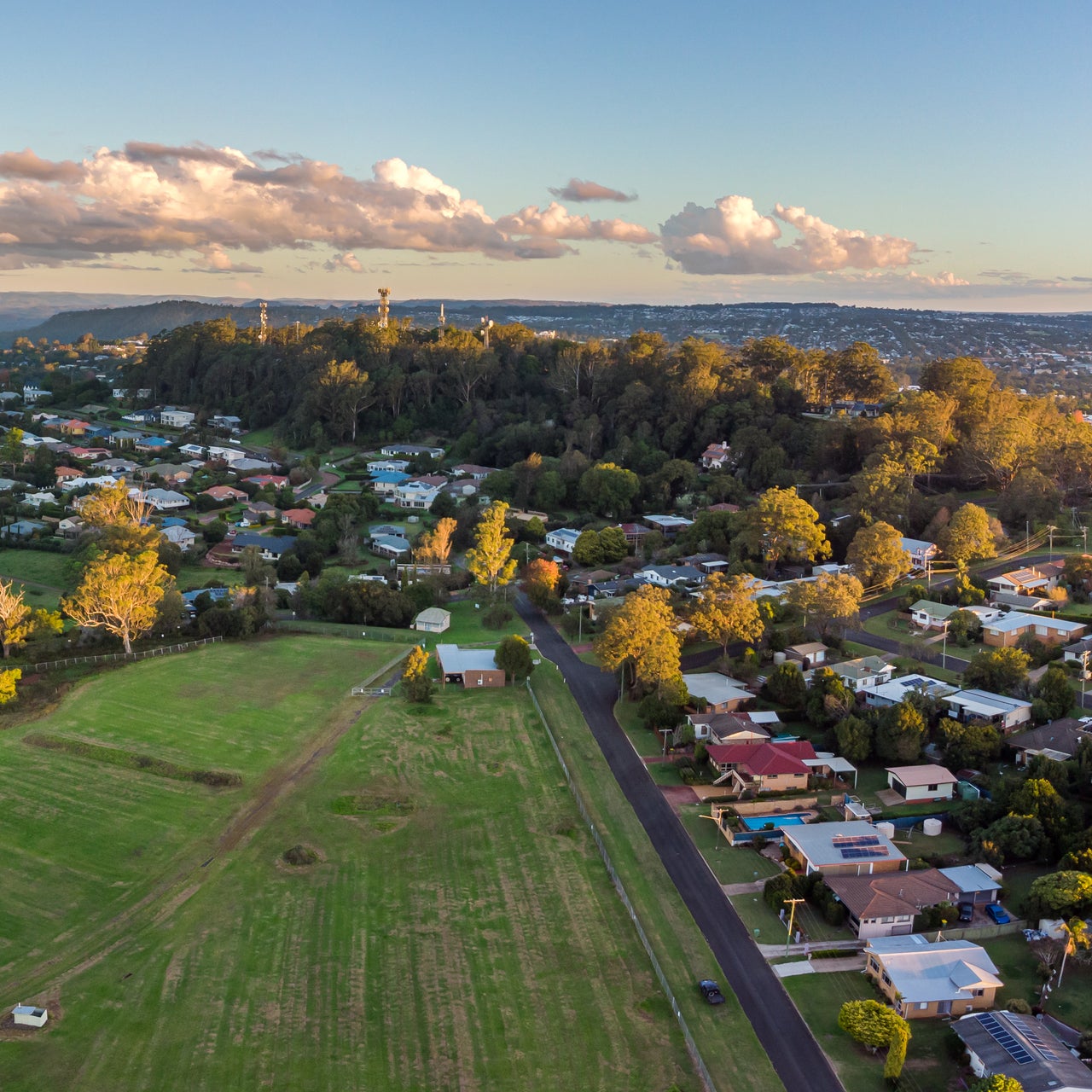 Aerial view of a suburban neighborhood with houses, streets, trees, and a swimming pool.