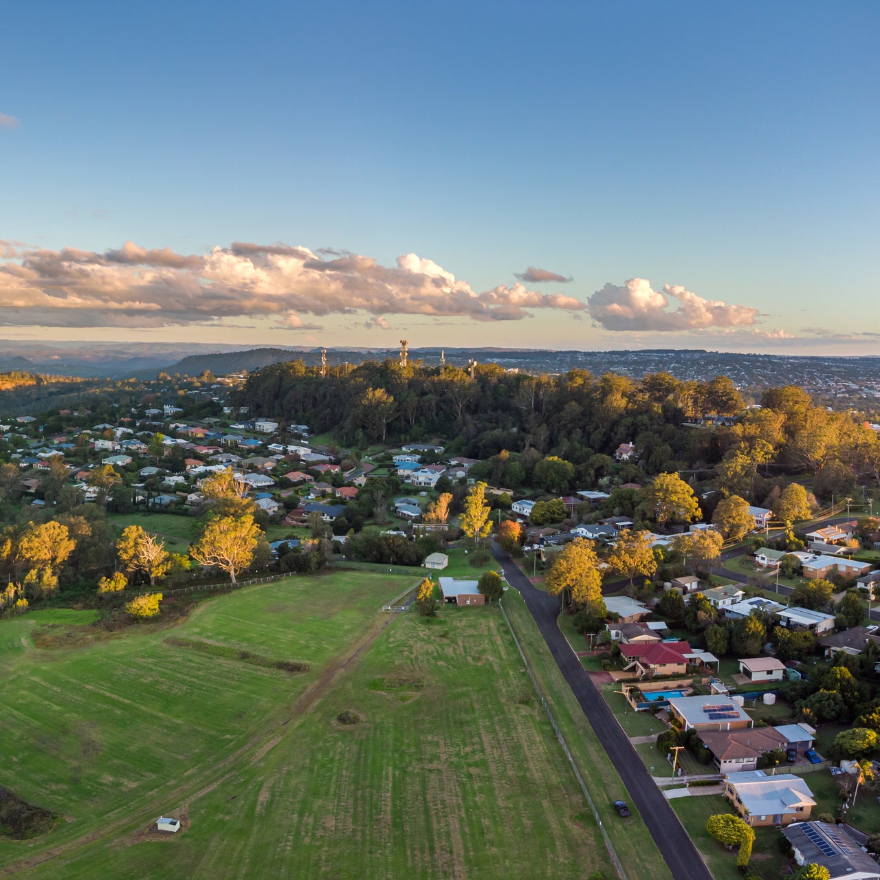Aerial view of a suburban neighborhood with houses, streets, trees, and a swimming pool.