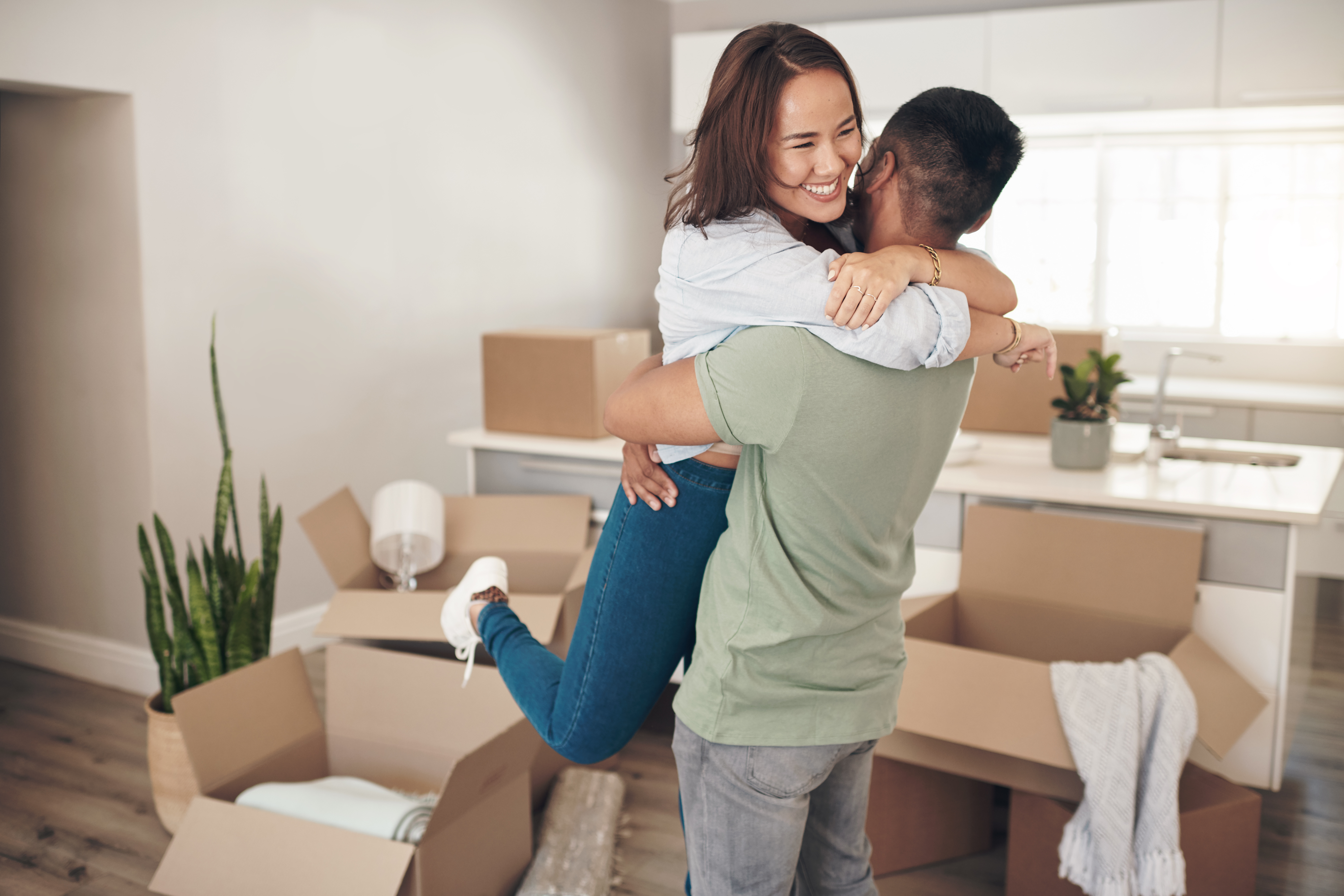Homebuyers jumping in each others arms with joy after buying a house.