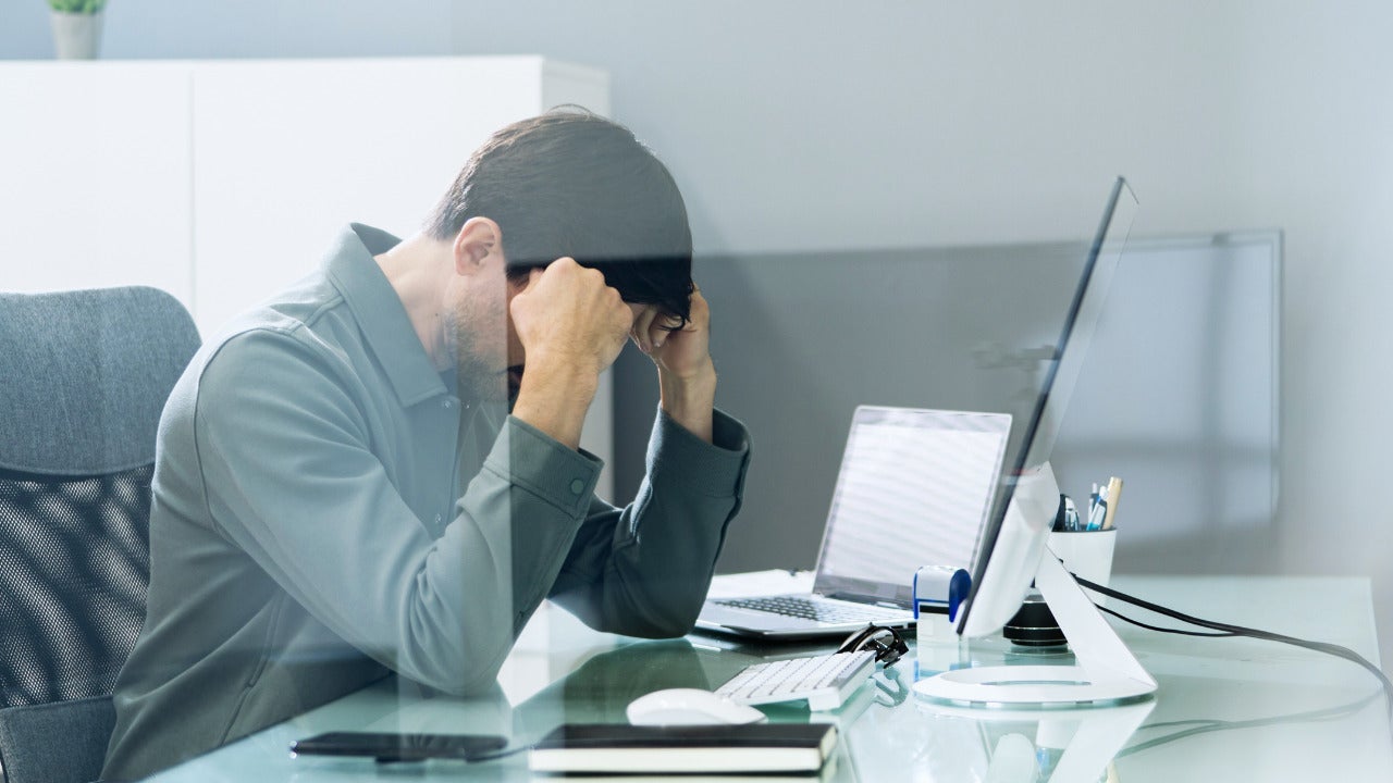 A person with their hands on their head showing frustration towards making a mistake related to cyber security