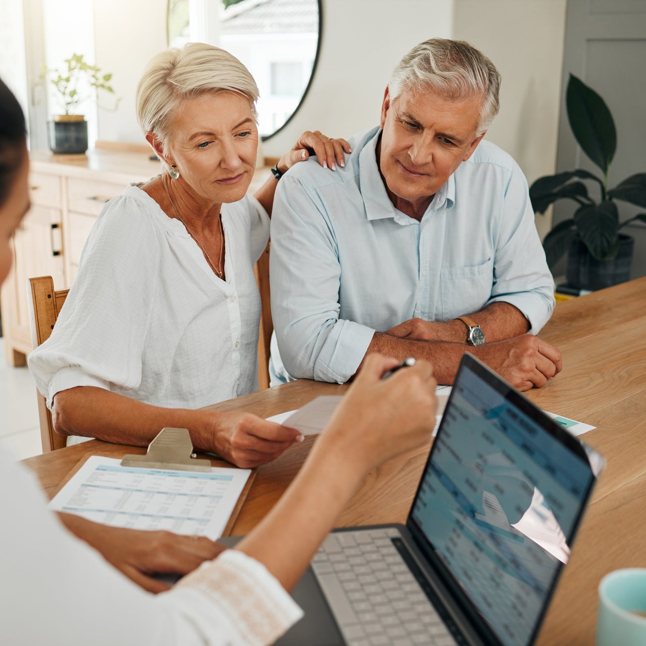 An elderly couple sitting across the table with an agent, discussing something.