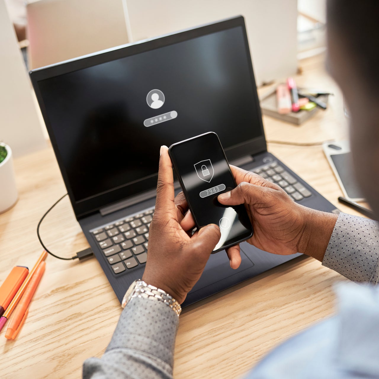 A real estate agent using multi factor authentication on his phone to connect to his laptop.