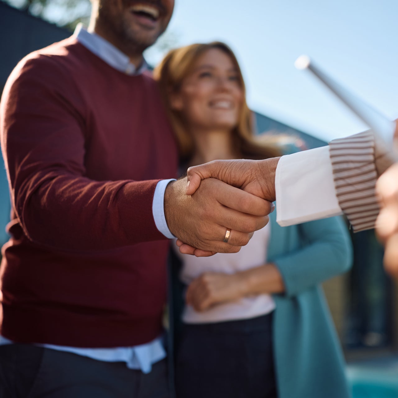 Photo of a couple shaking hands wit a real estate agent
