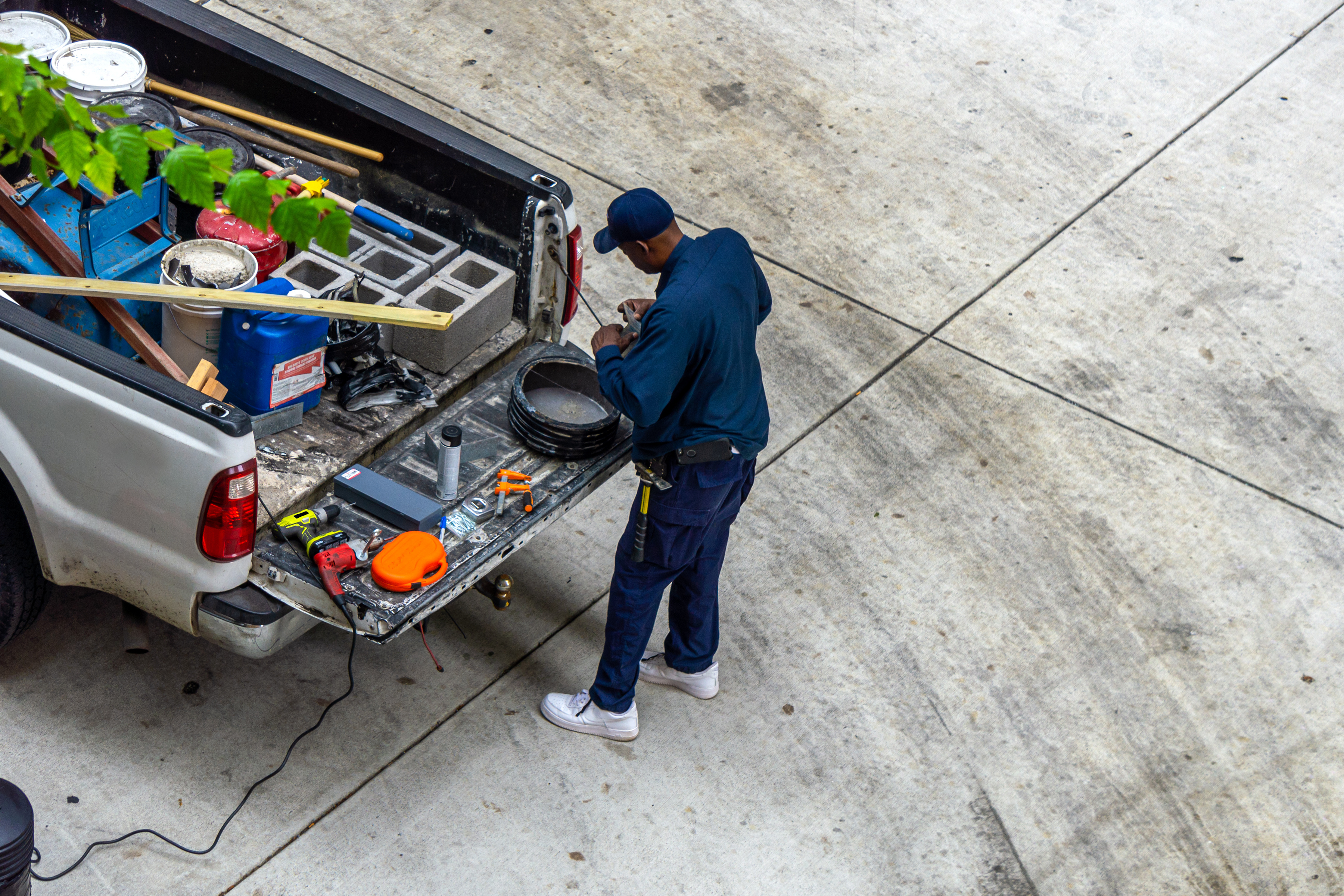 A repairman grabs tools from the back of his work truck at a house.