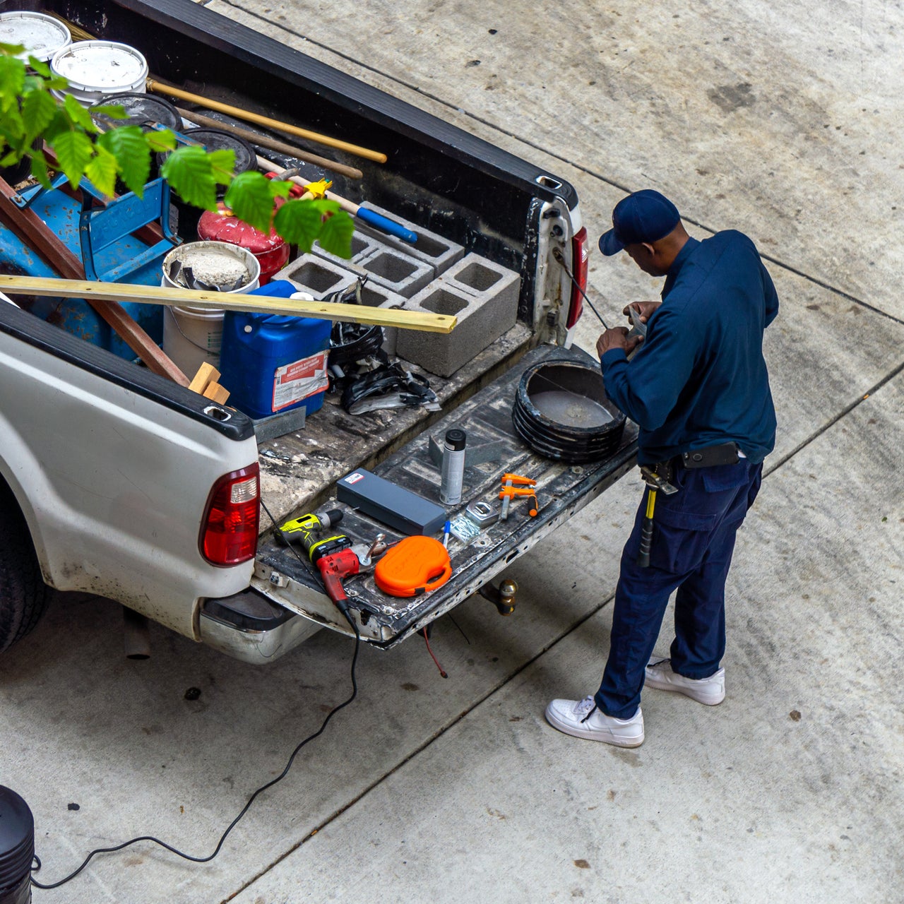 A repairman grabs tools from the back of his work truck at a house.