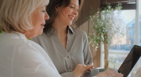 Two persons looking at a screen showing Cotality OneHomeowner and laughing