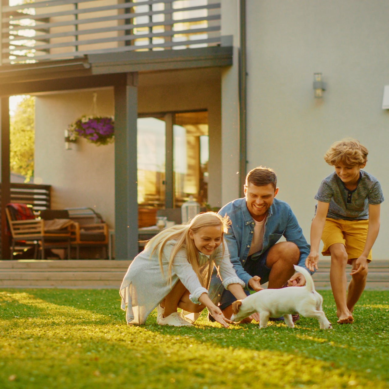 A couple and their child are seen playing with their pet in an outdoor setup.