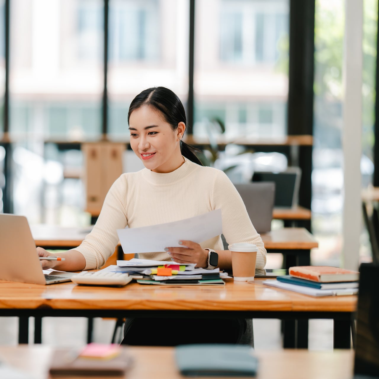 A lady is seen working on a laptop kept on a desk.