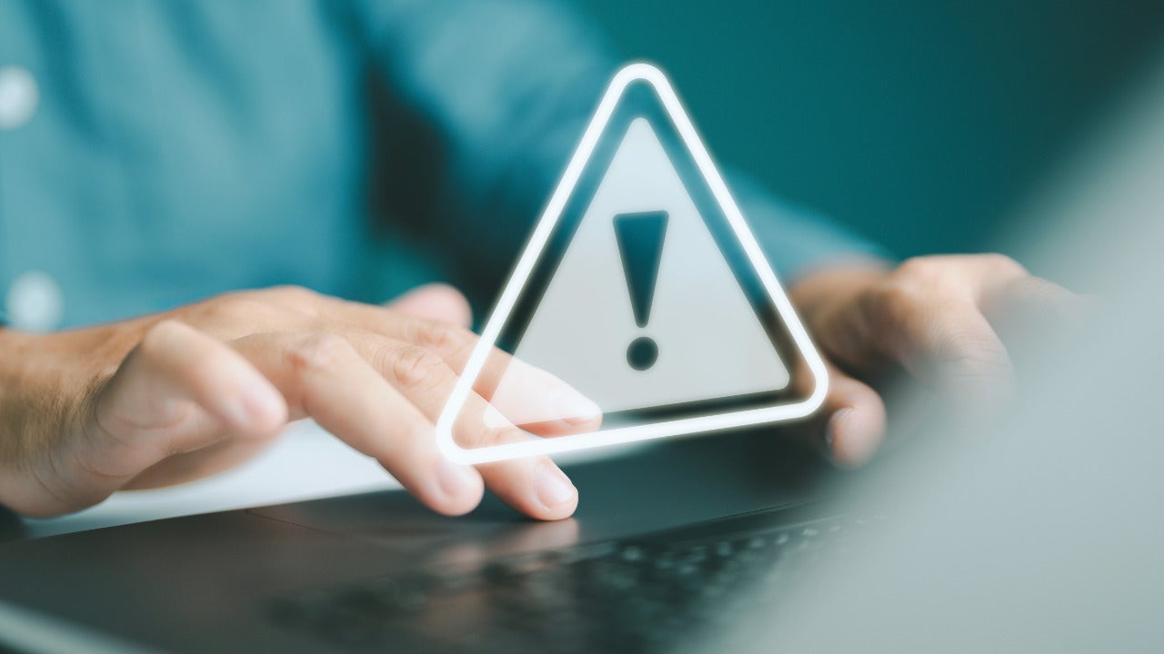 Someone interacting with a keyboard and an overlay of a warning symbol