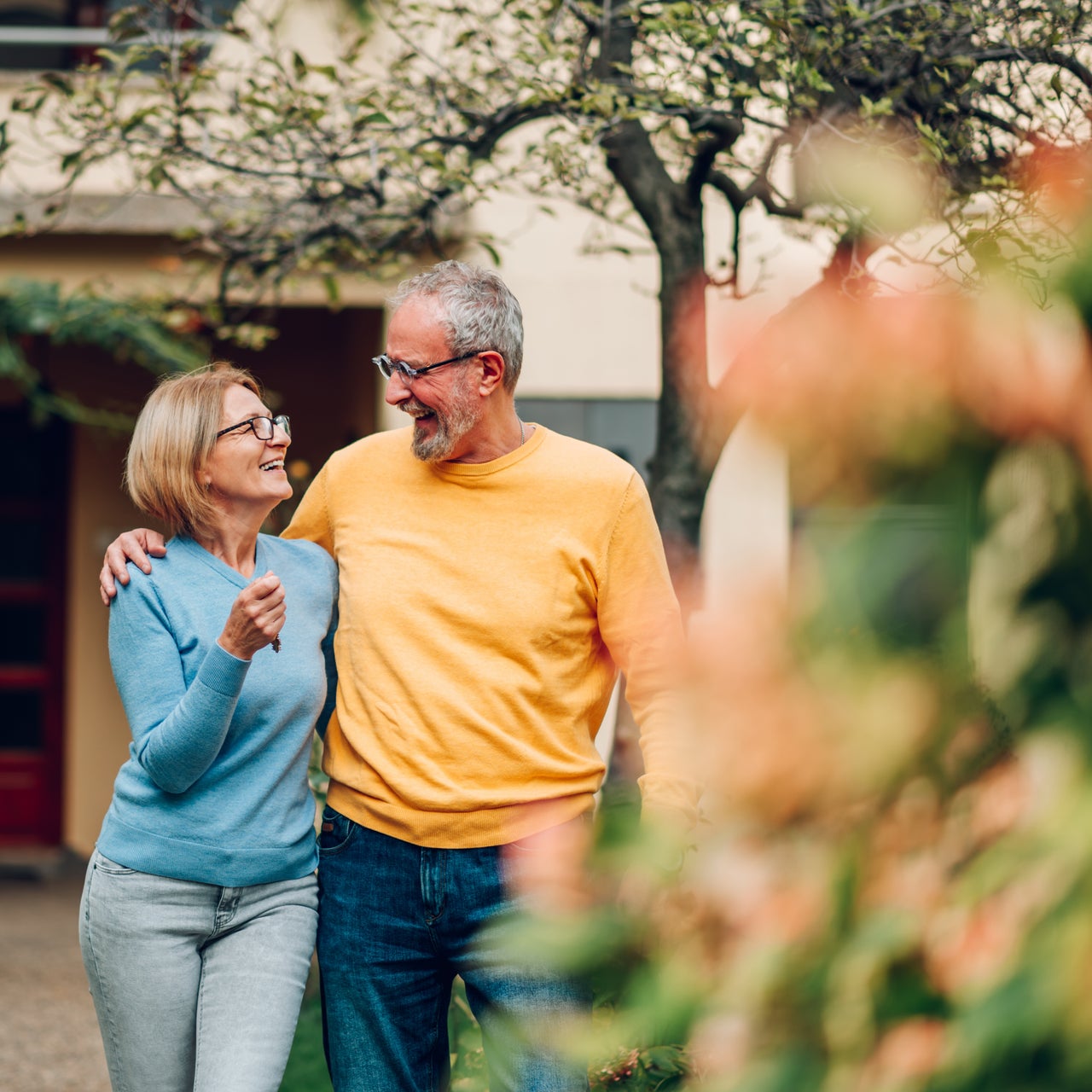 A man and woman smiling and looking at each other while the man has his arm around the woman's shoulder