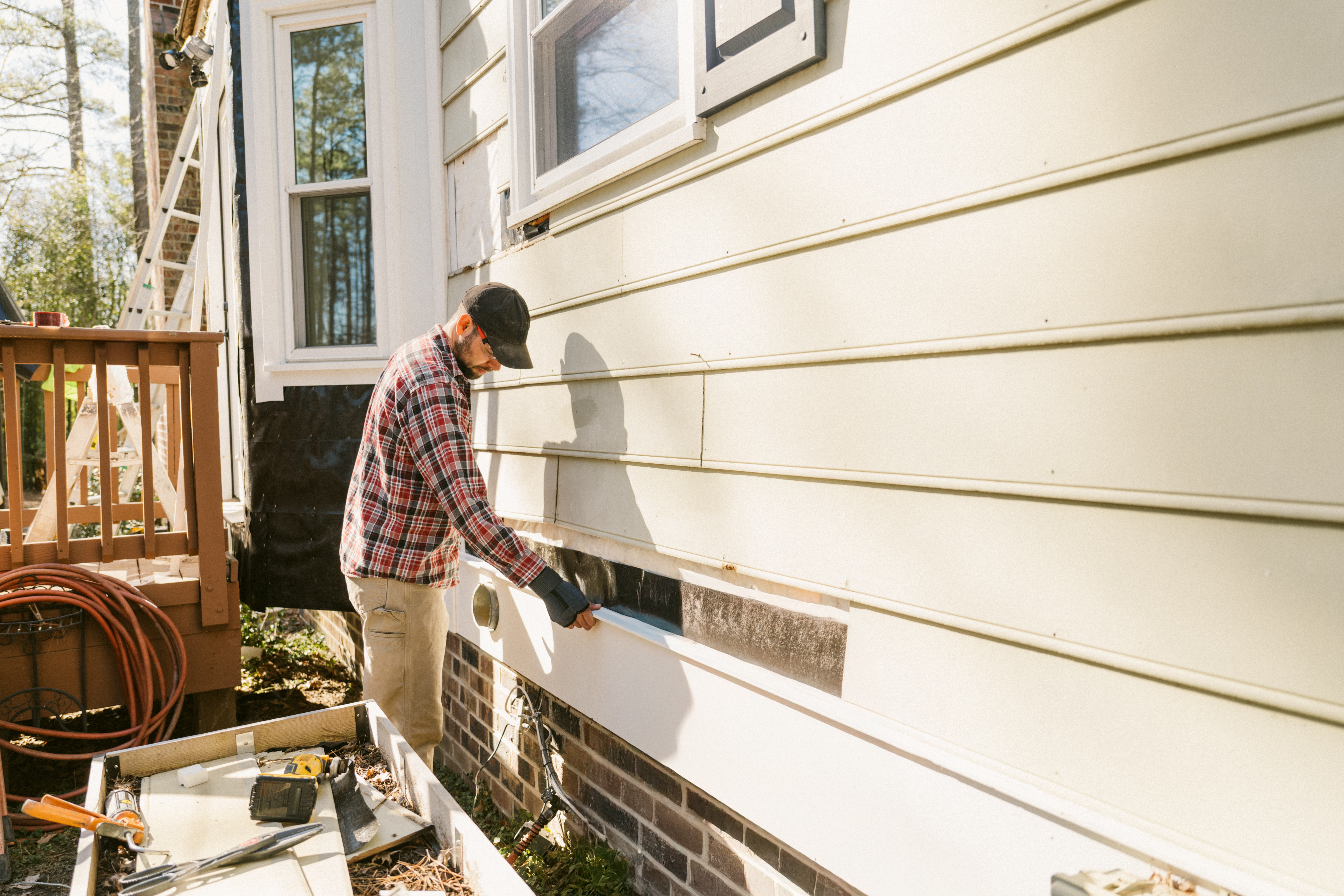 A contractor performs repairs on the exterior of a house, representing the on-site work that leads to supplement requests.
