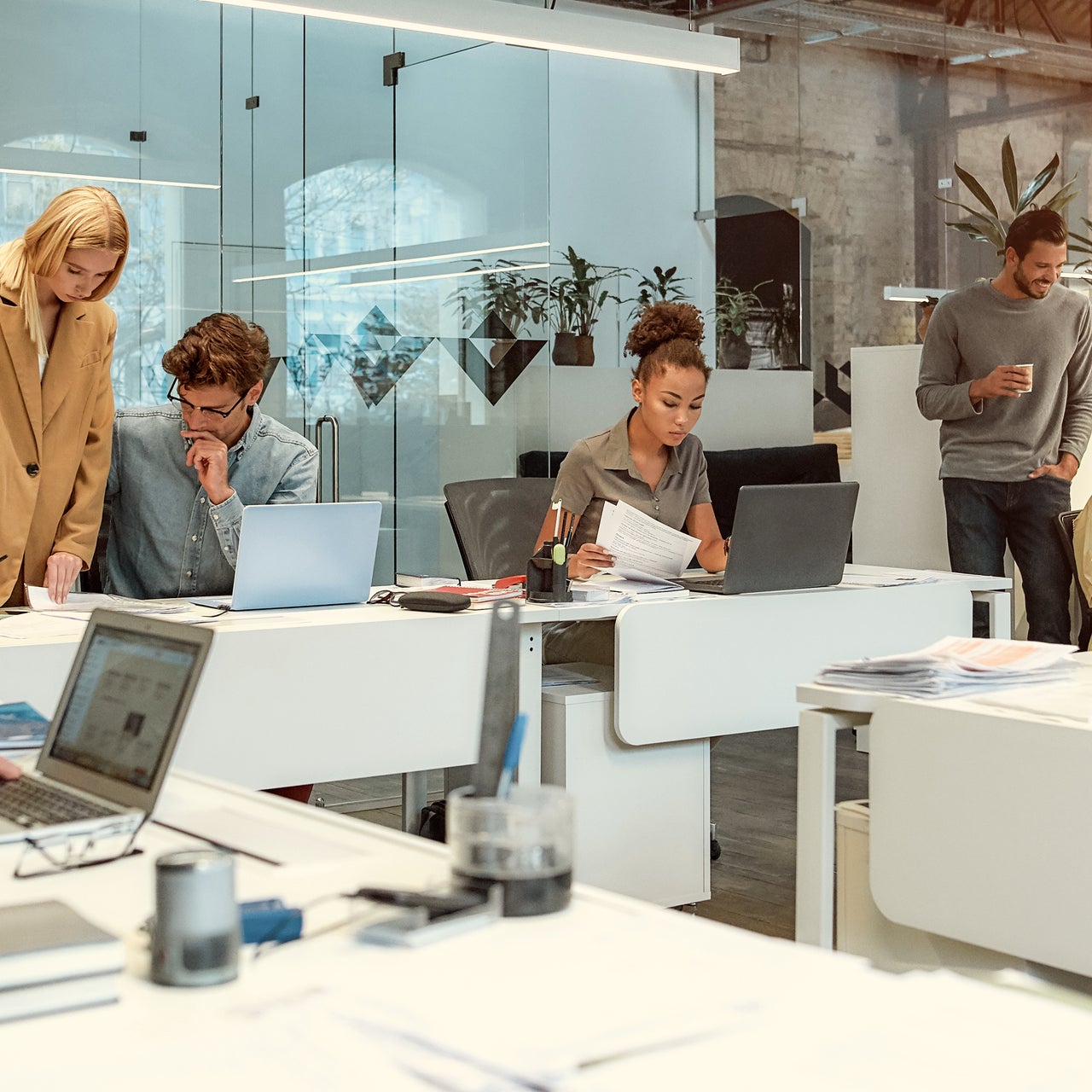 An office set up with people seen working on their desks, and appearing busy.