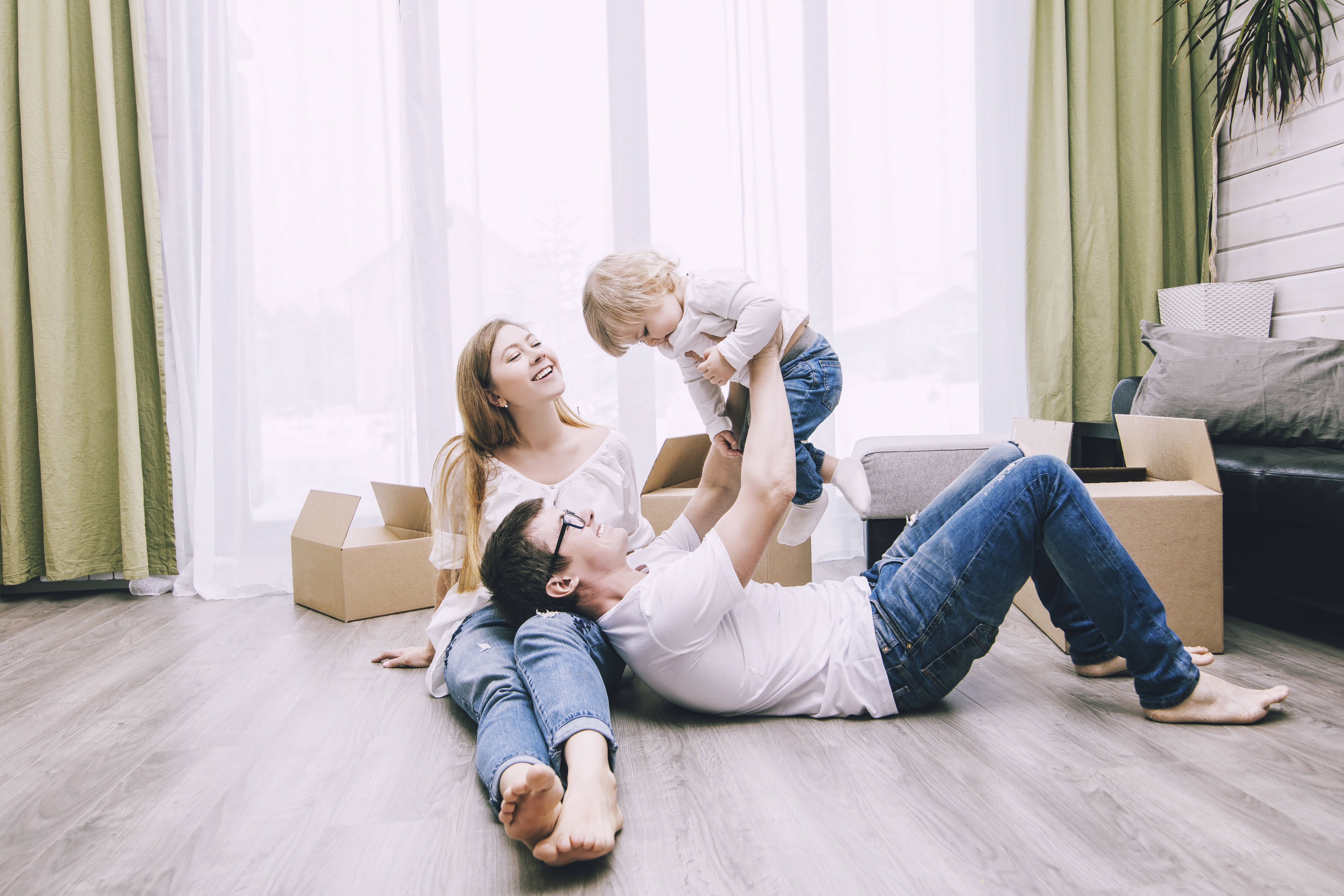 Two parents playing with their child in their new house with moving boxes.