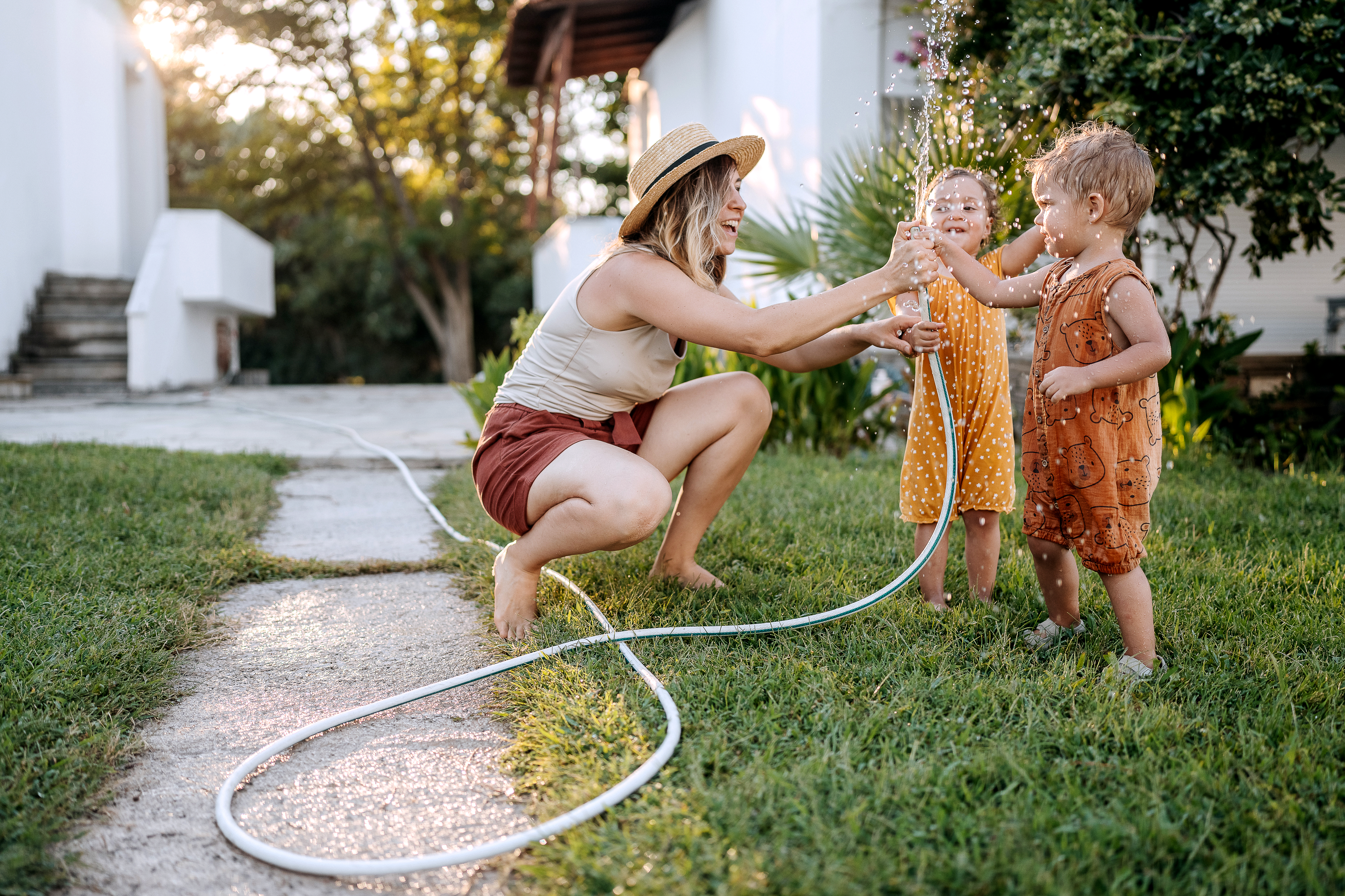 Mother and kids paying with hose in yard