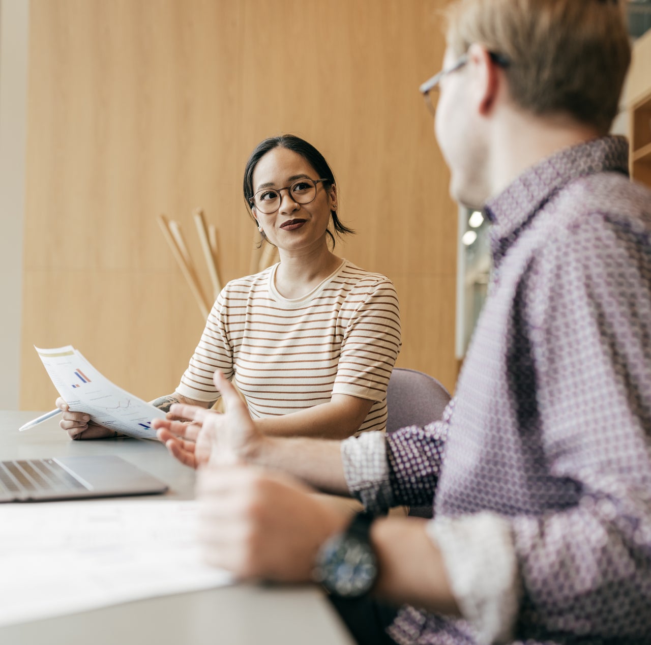 A woman is seen holding a document while having a discussion with another person.
