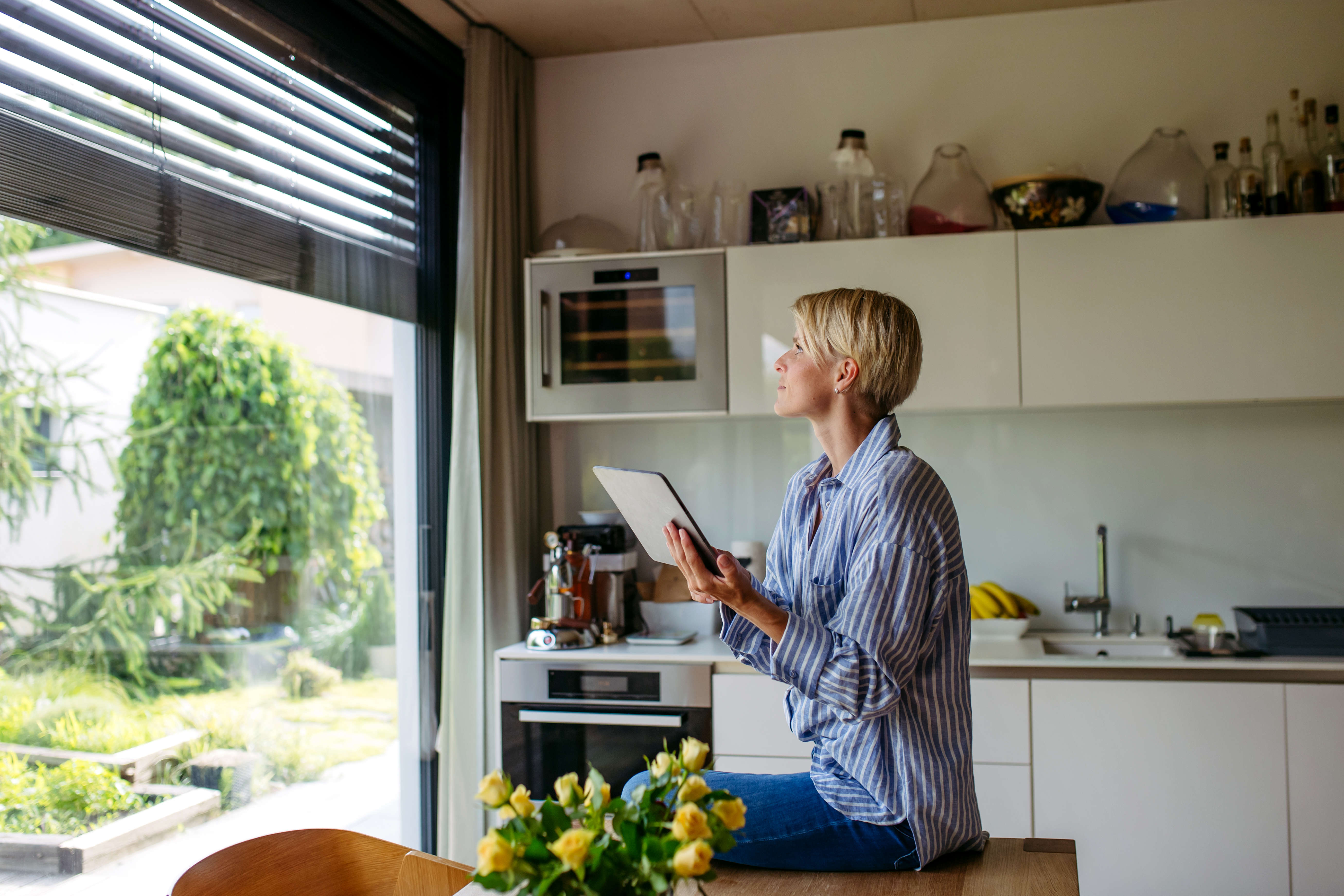 Beautiful woman closing metal blinds on smart home automation system. Smart home technology for sustainable living.