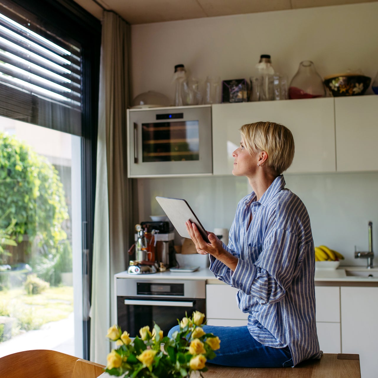 Beautiful woman closing metal blinds on smart home automation system. Smart home technology for sustainable living.