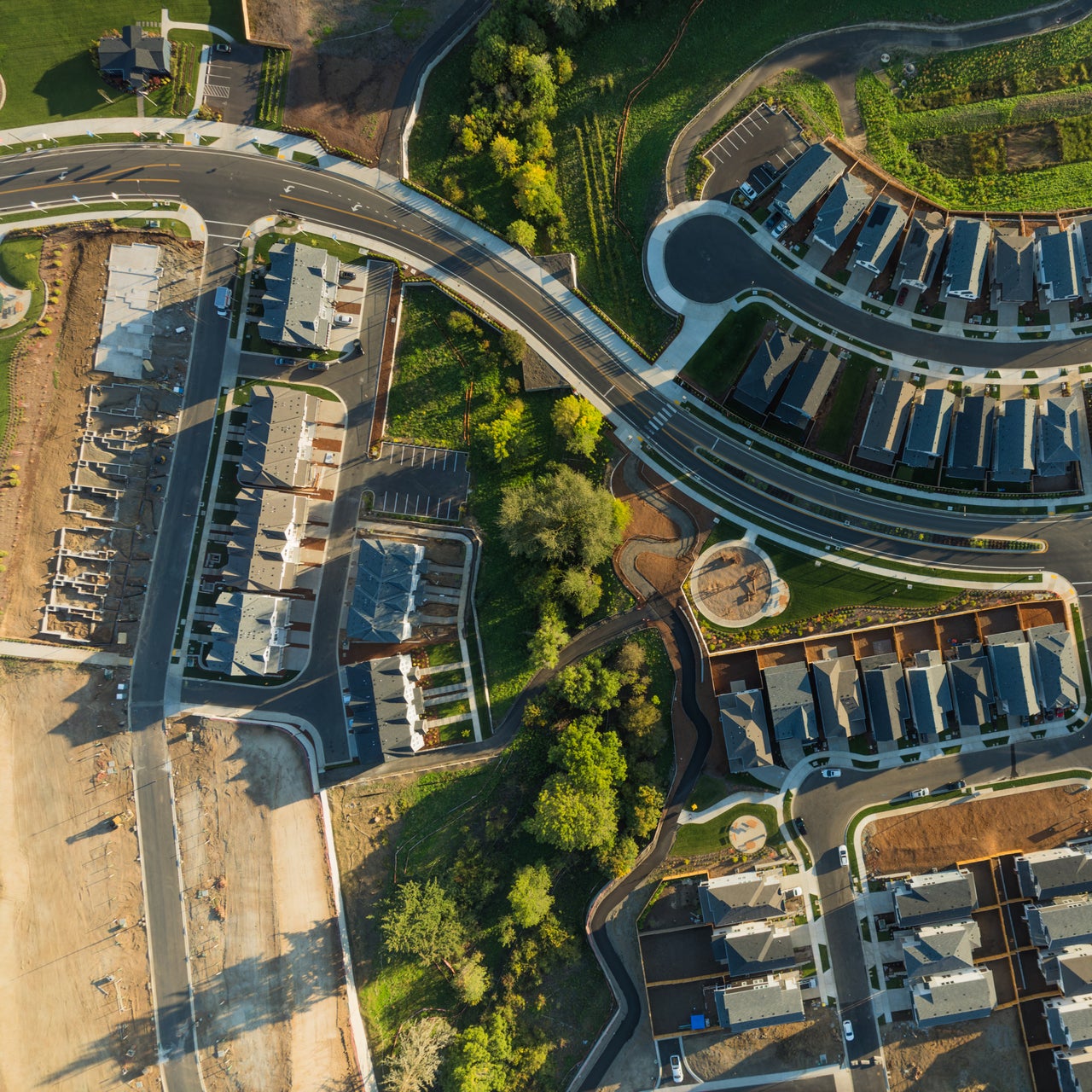 An aerial view of a residential area with houses, roads, and green spaces.