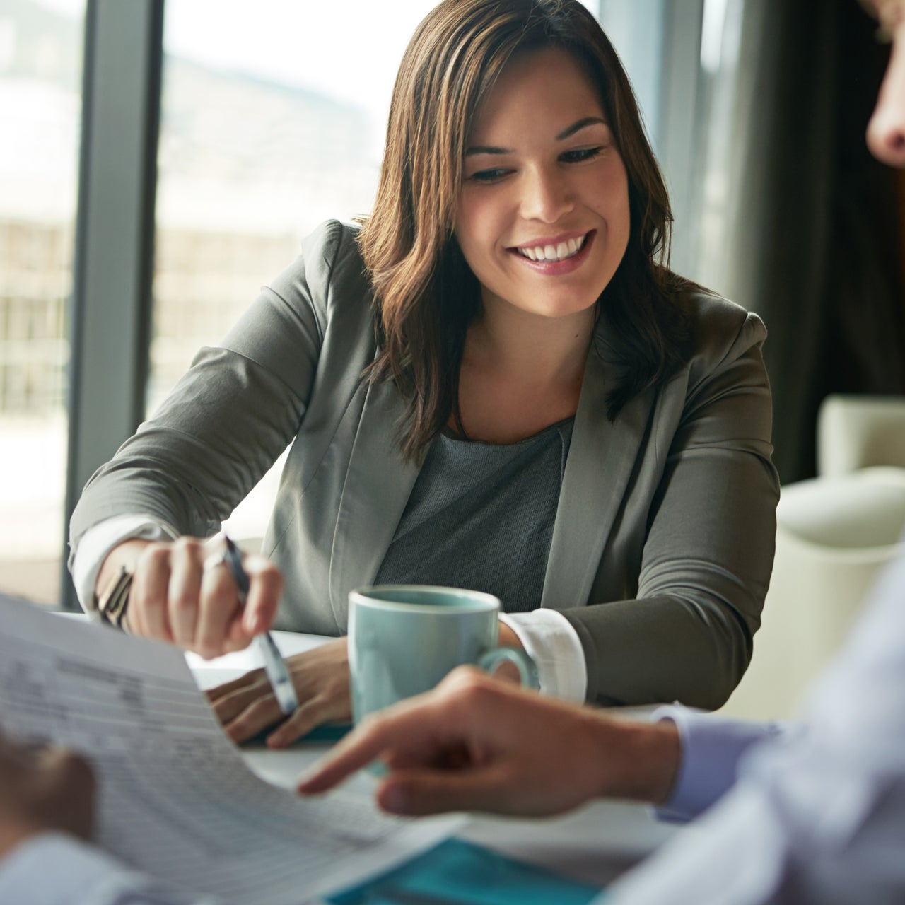 A woman is seen smiling while looking at documents.